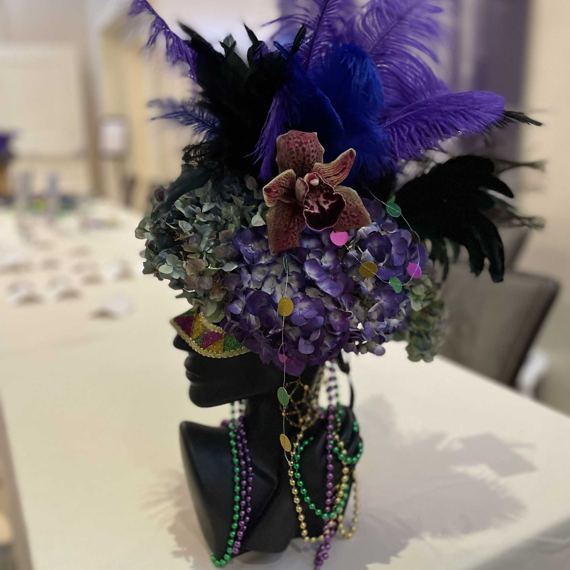 Purple floral headpiece with feathers on a black mannequin bust