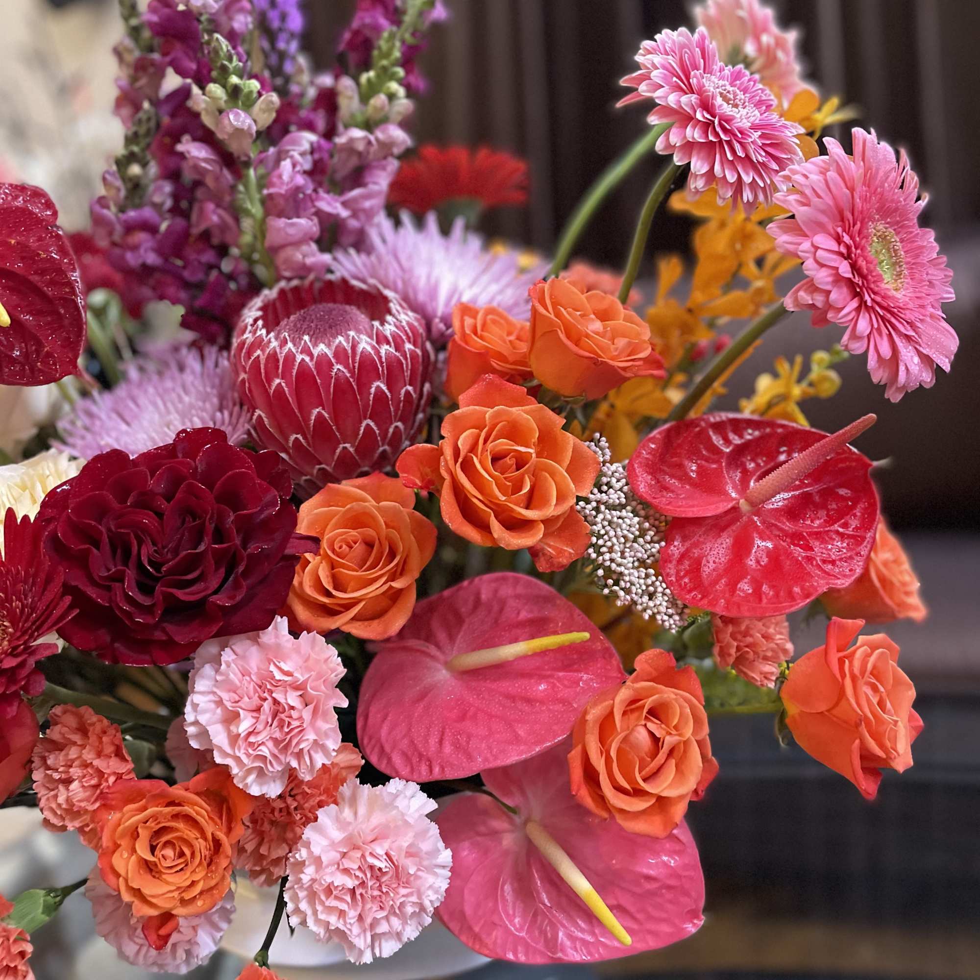 Bright mixed bouquet with orange roses, pink anthuriums, and pink gerbera daisies