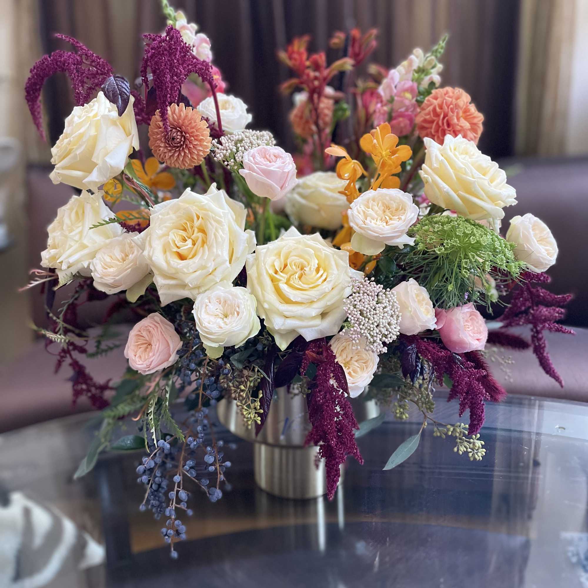 Mixed bouquet of cream, pink, and orange flowers in a metal vase