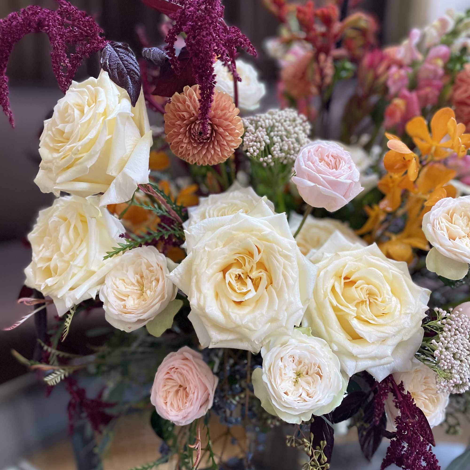 Cream and blush roses with burgundy hanging blooms in a bouquet