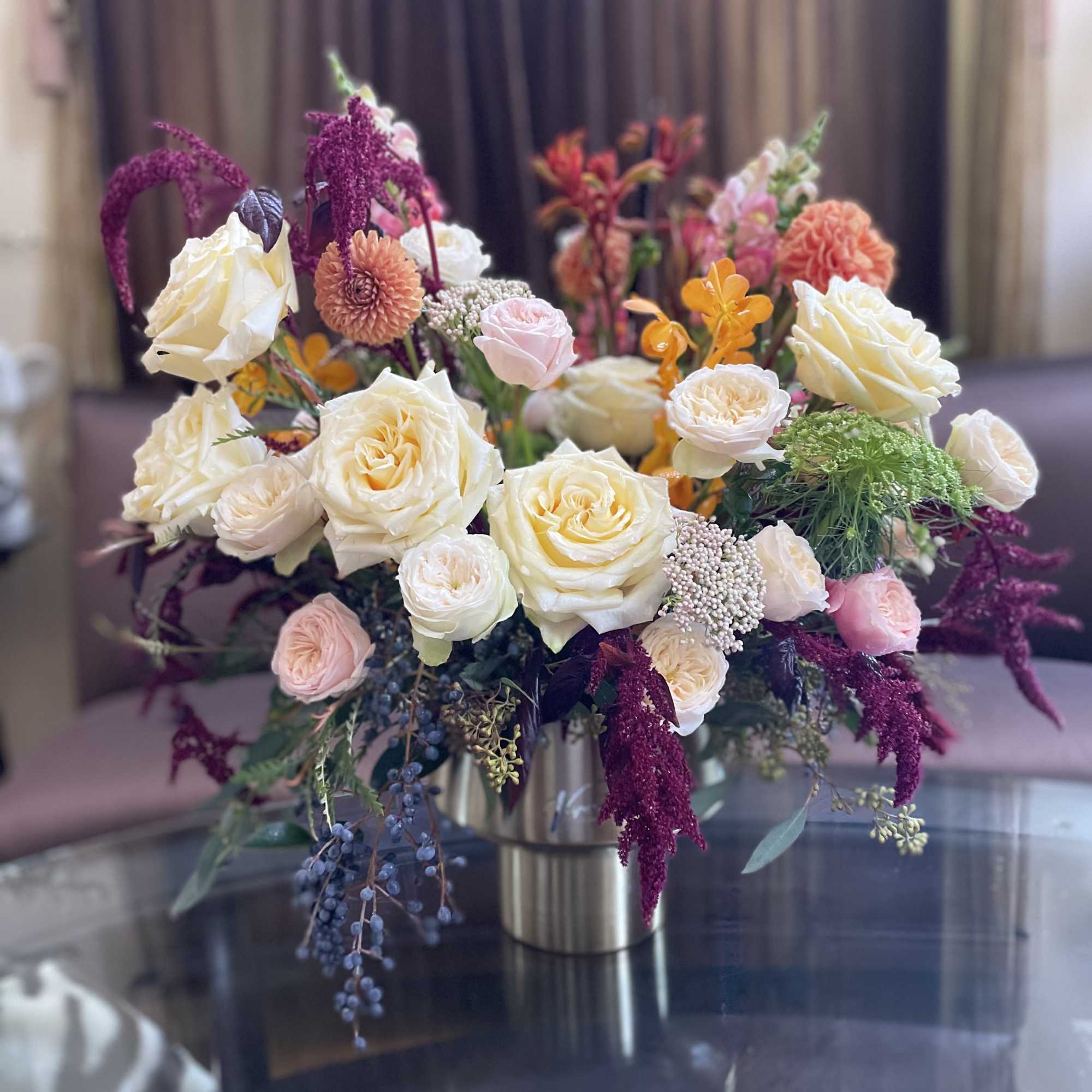 Mixed bouquet of cream, pink, and purple flowers in a metal vase