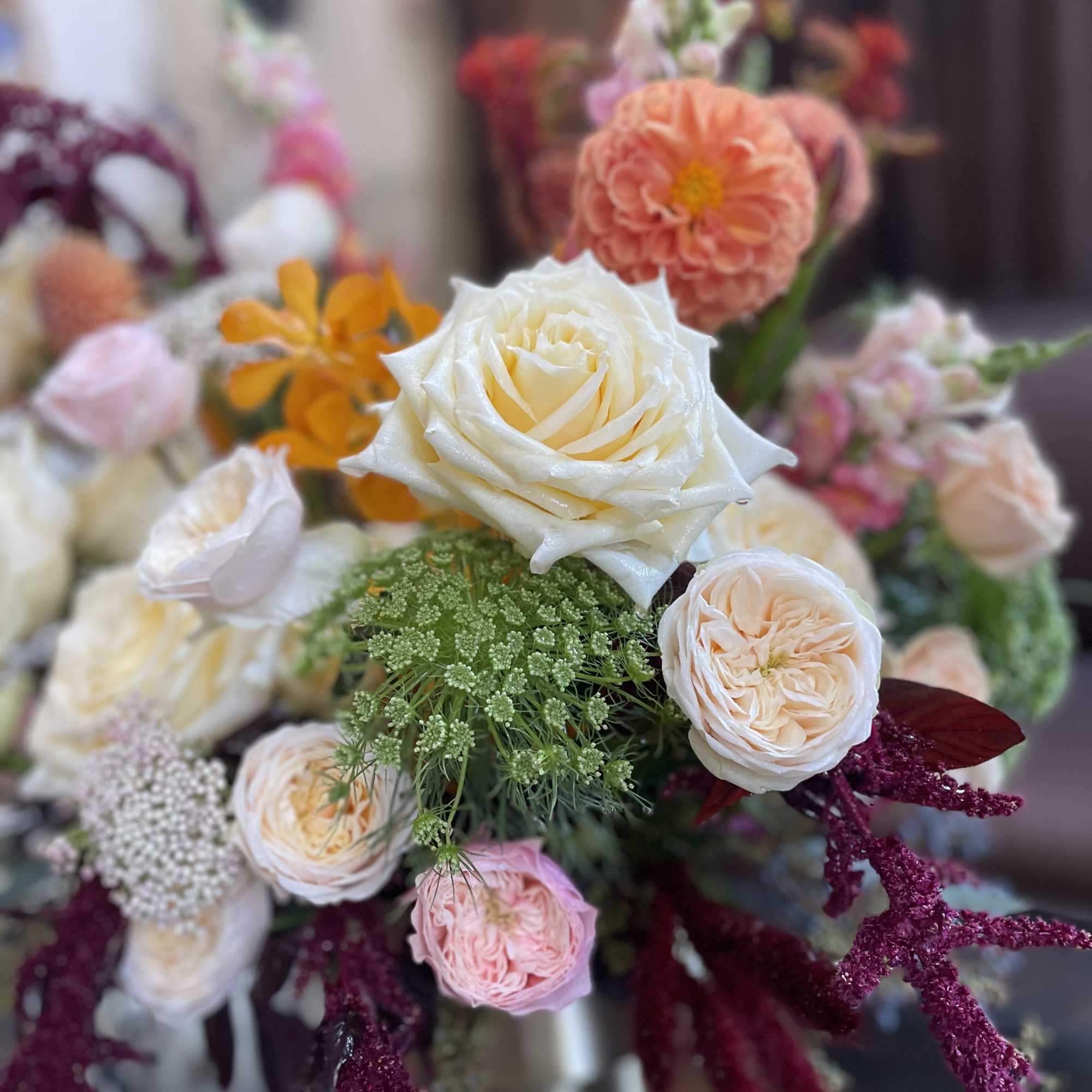 Bouquet of cream, peach, and pink roses with orange blooms