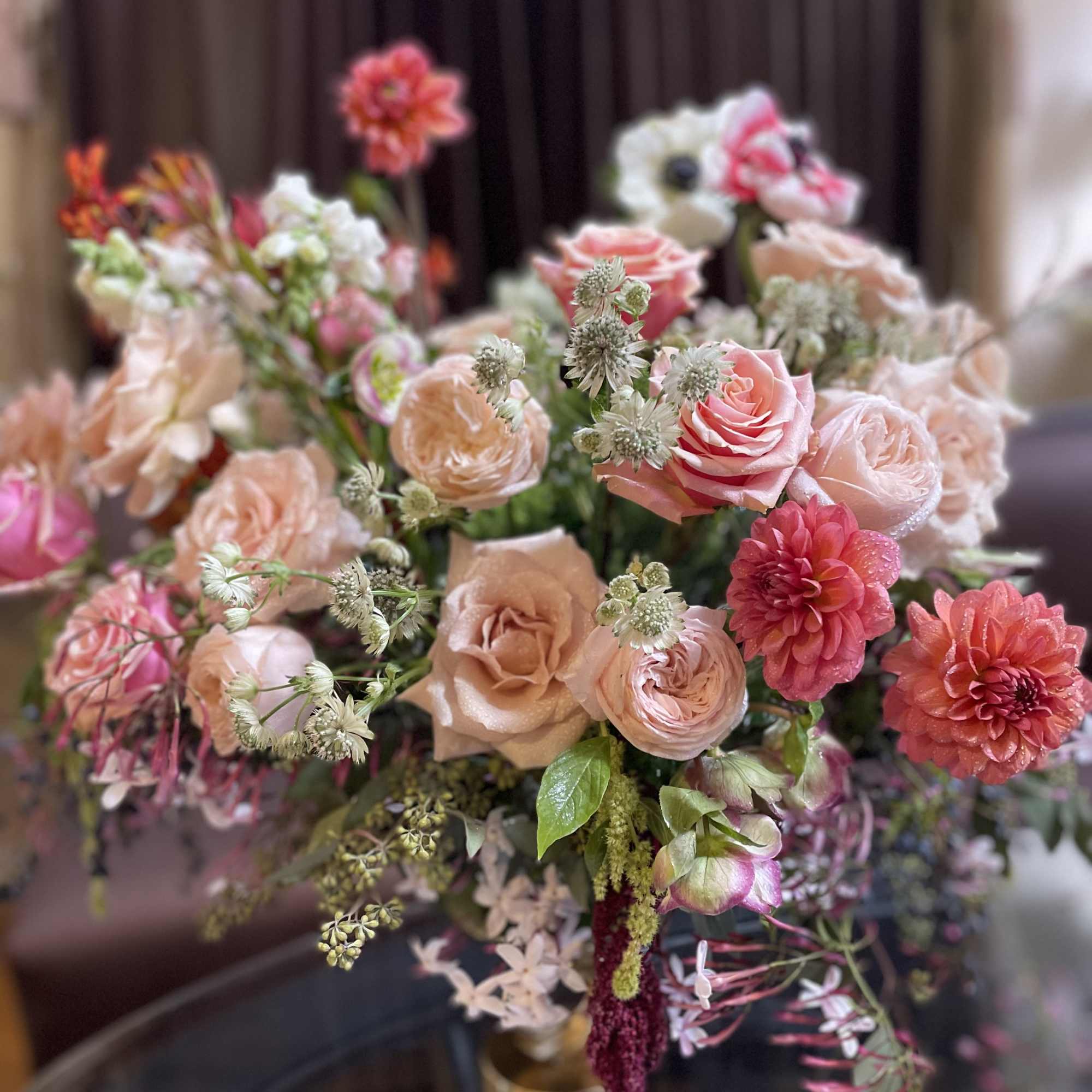 Bouquet of pink and peach roses with coral dahlias in a vase