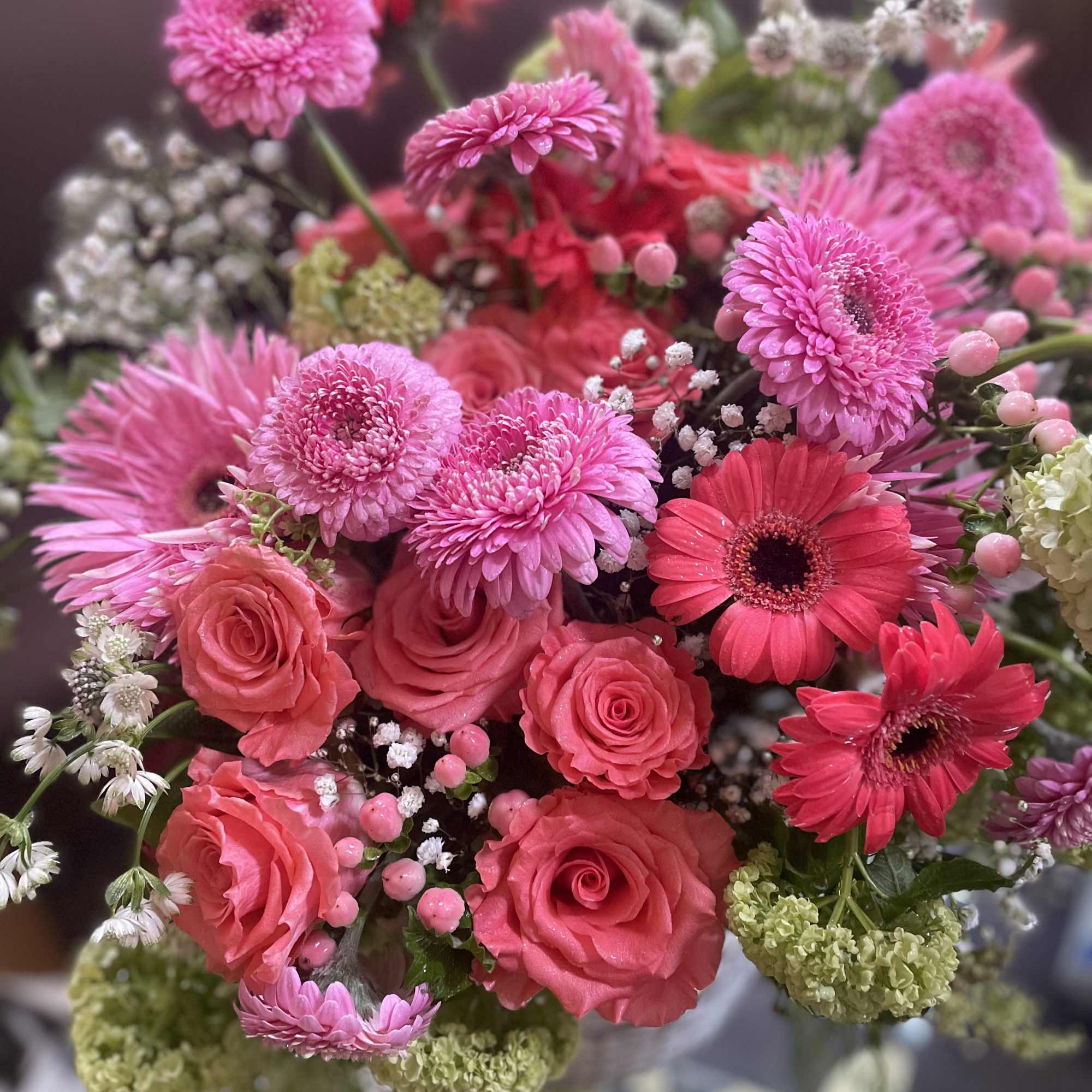 Bouquet of pink gerbera daisies and roses with small white filler flowers
