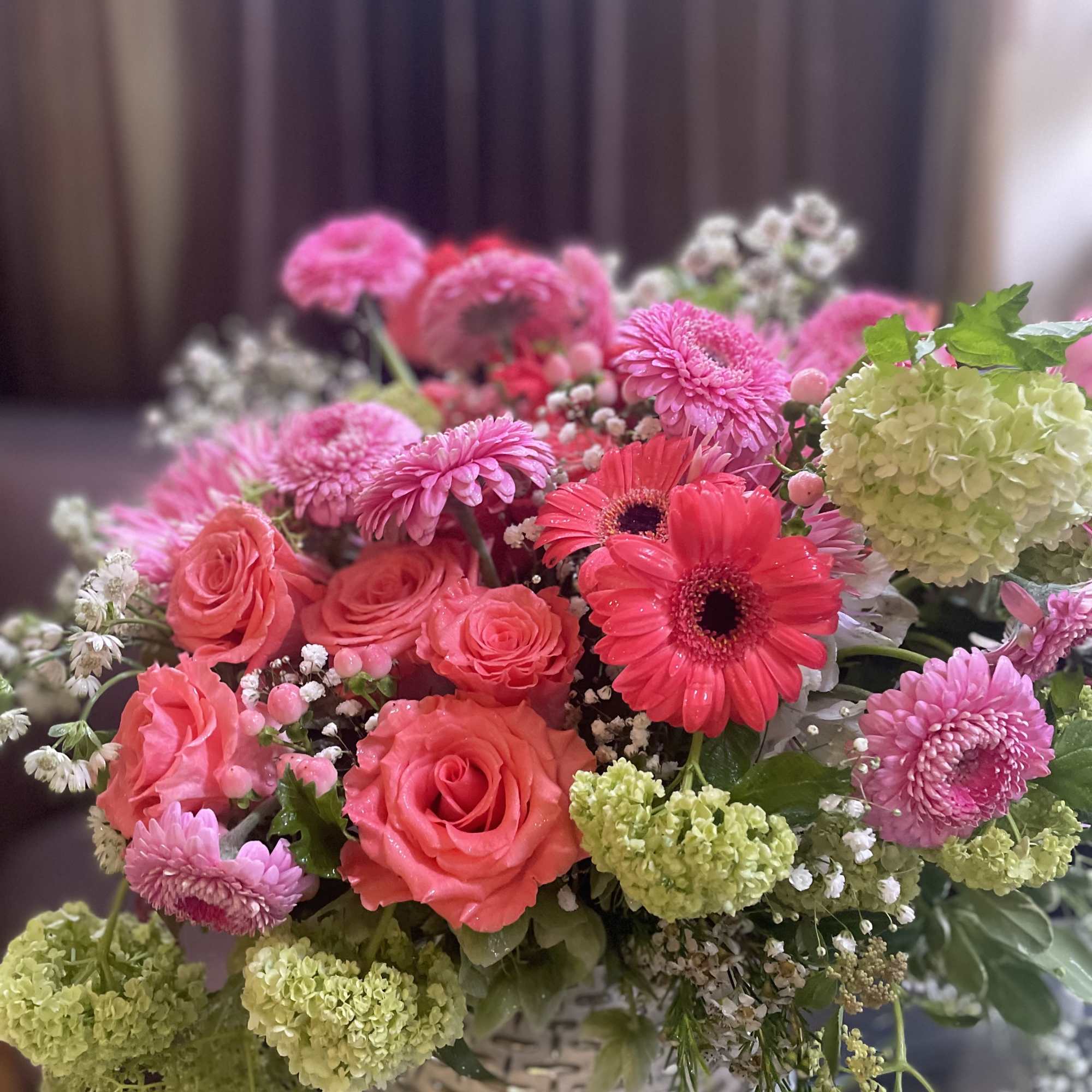 Pink roses and gerbera daisies in a white woven vase