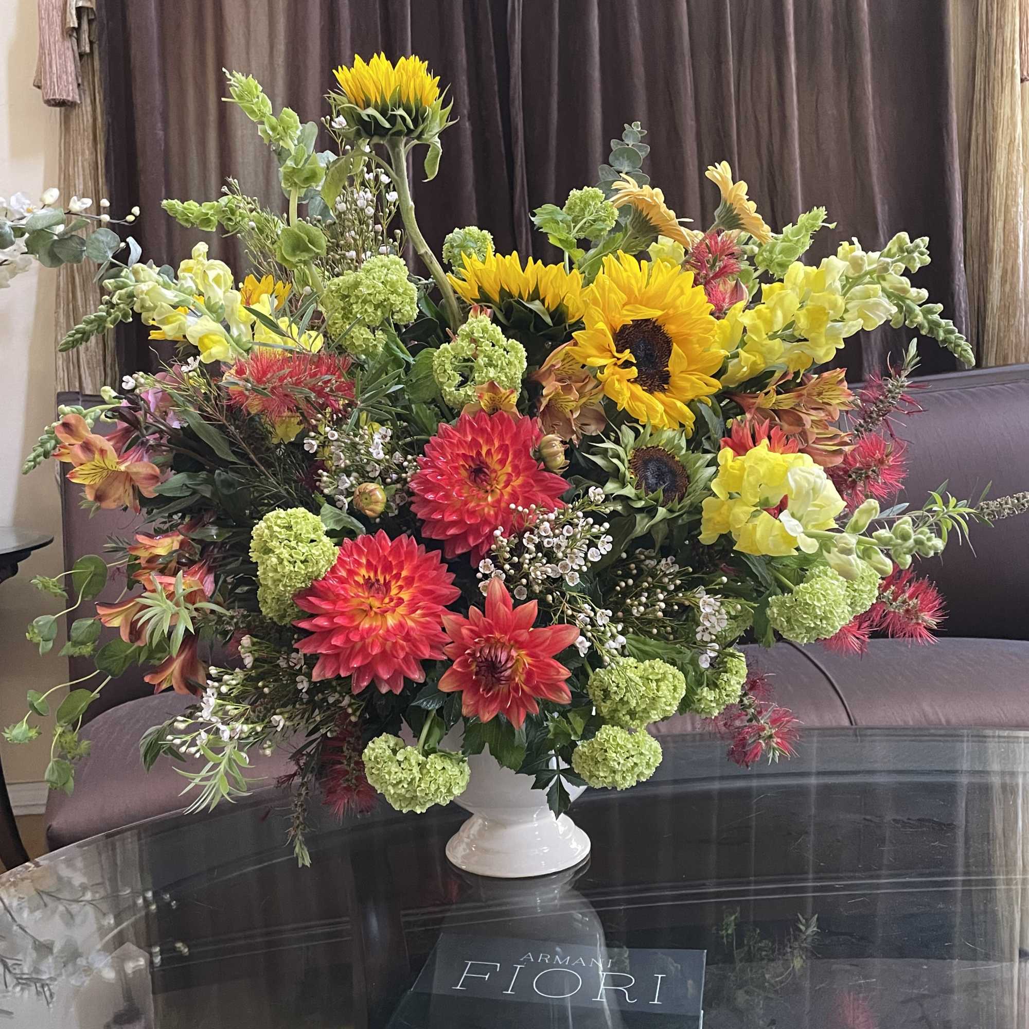 Large mixed flower arrangement in a white vase with sunflowers and dahlias