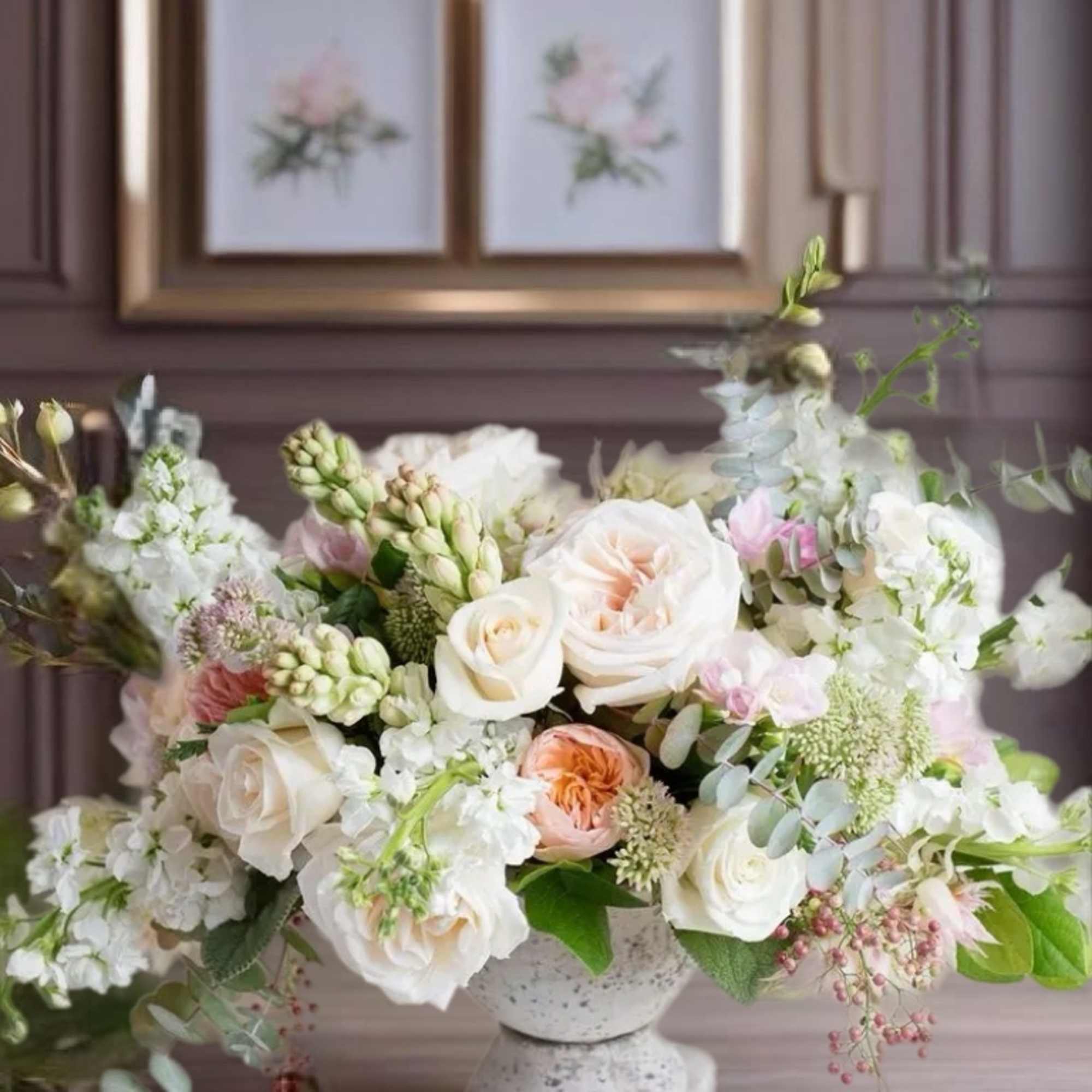 White and blush floral arrangement in a stone pedestal vase