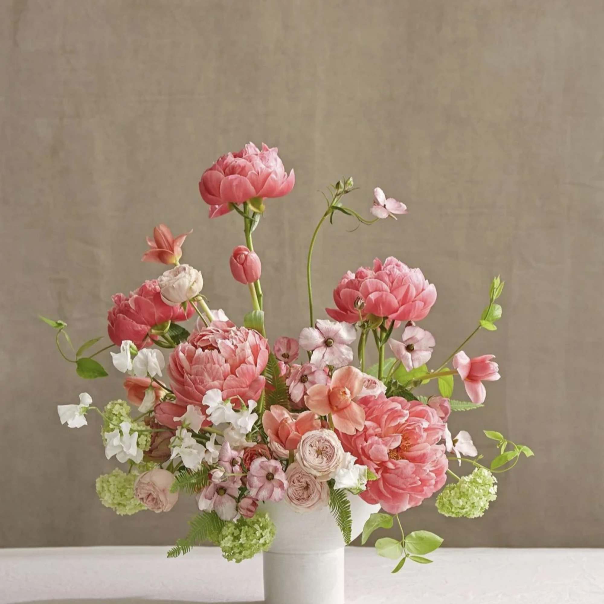 Pink floral arrangement in a white vase with airy stems
