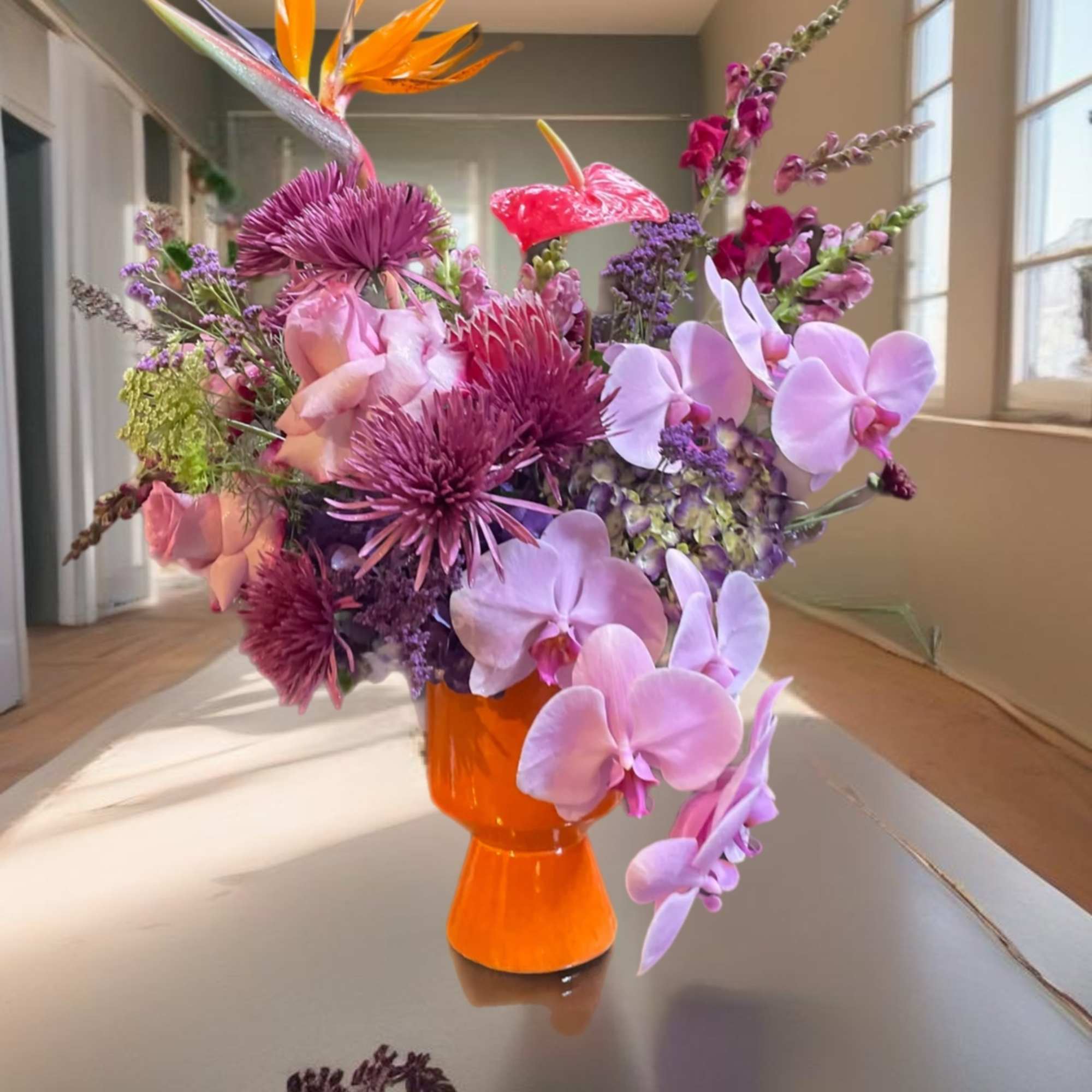 Colorful bouquet in an orange vase with orchids and tropical blooms