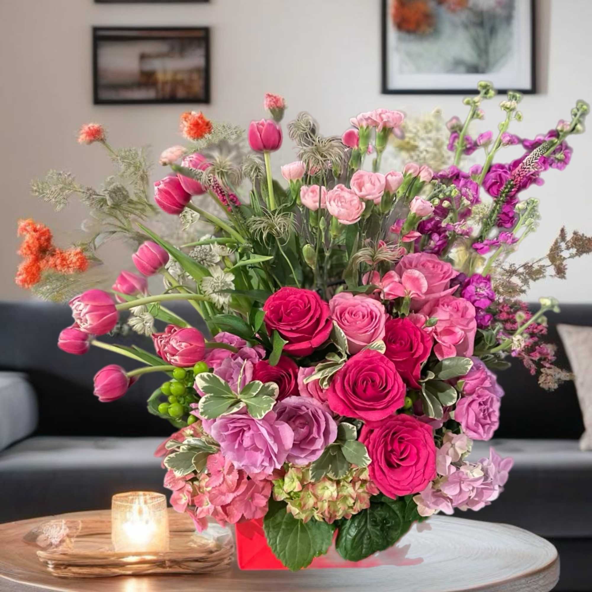 Pink and purple mixed flower arrangement in a red box on a table
