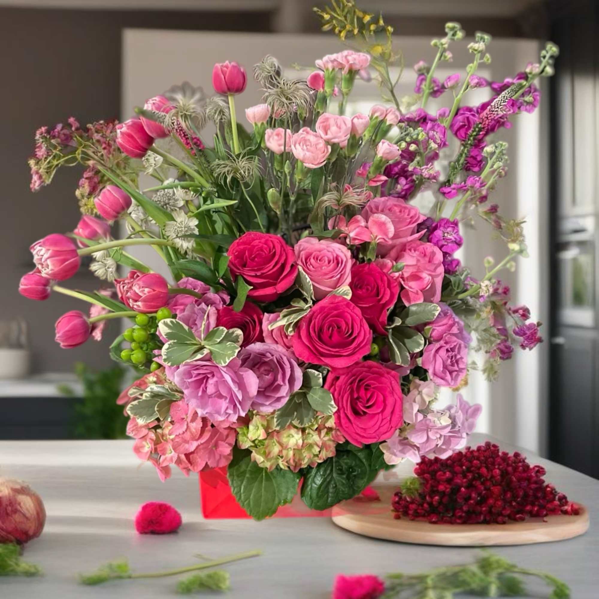 Pink and purple mixed flower arrangement in a red container