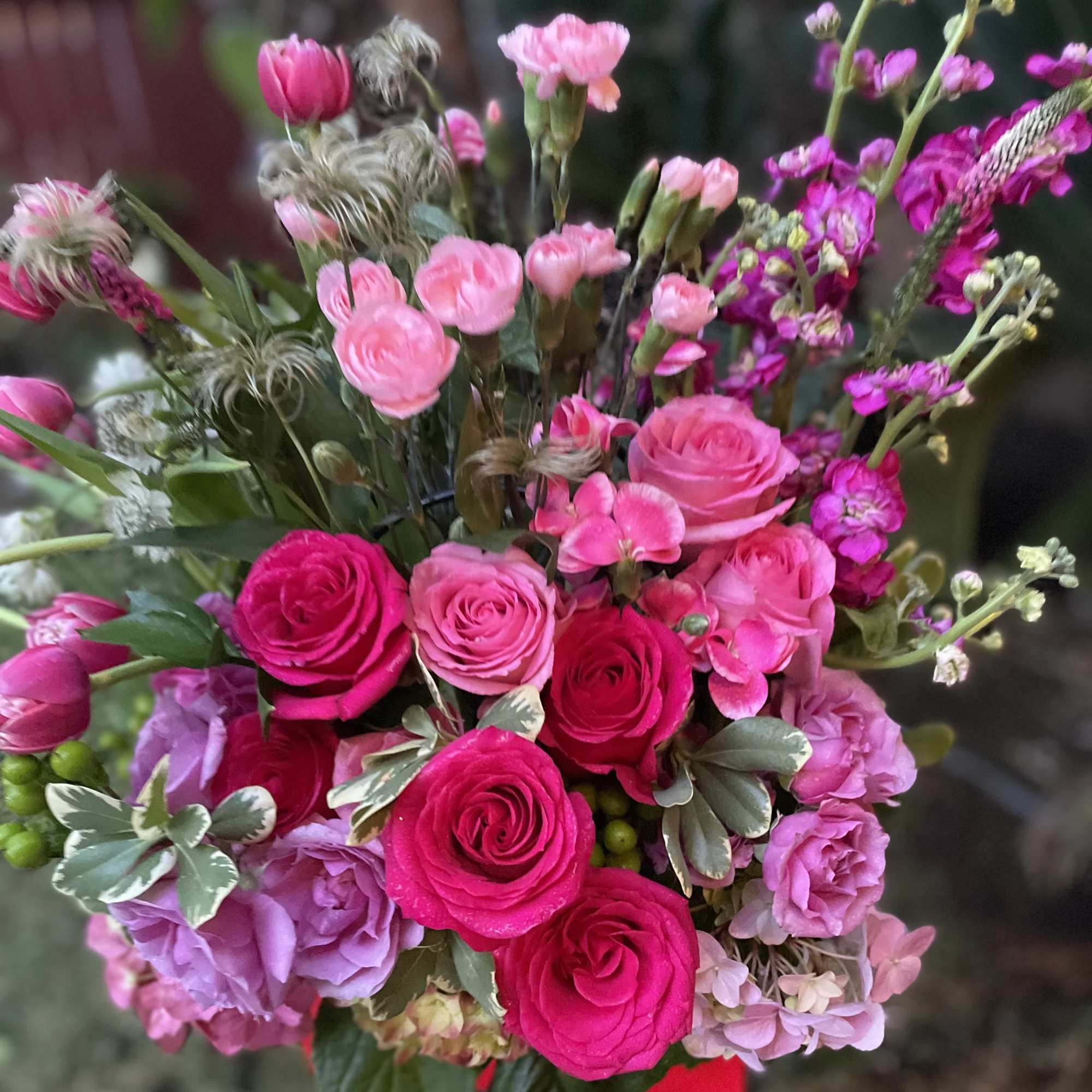 Bouquet of pink and magenta roses with purple blooms in a vase