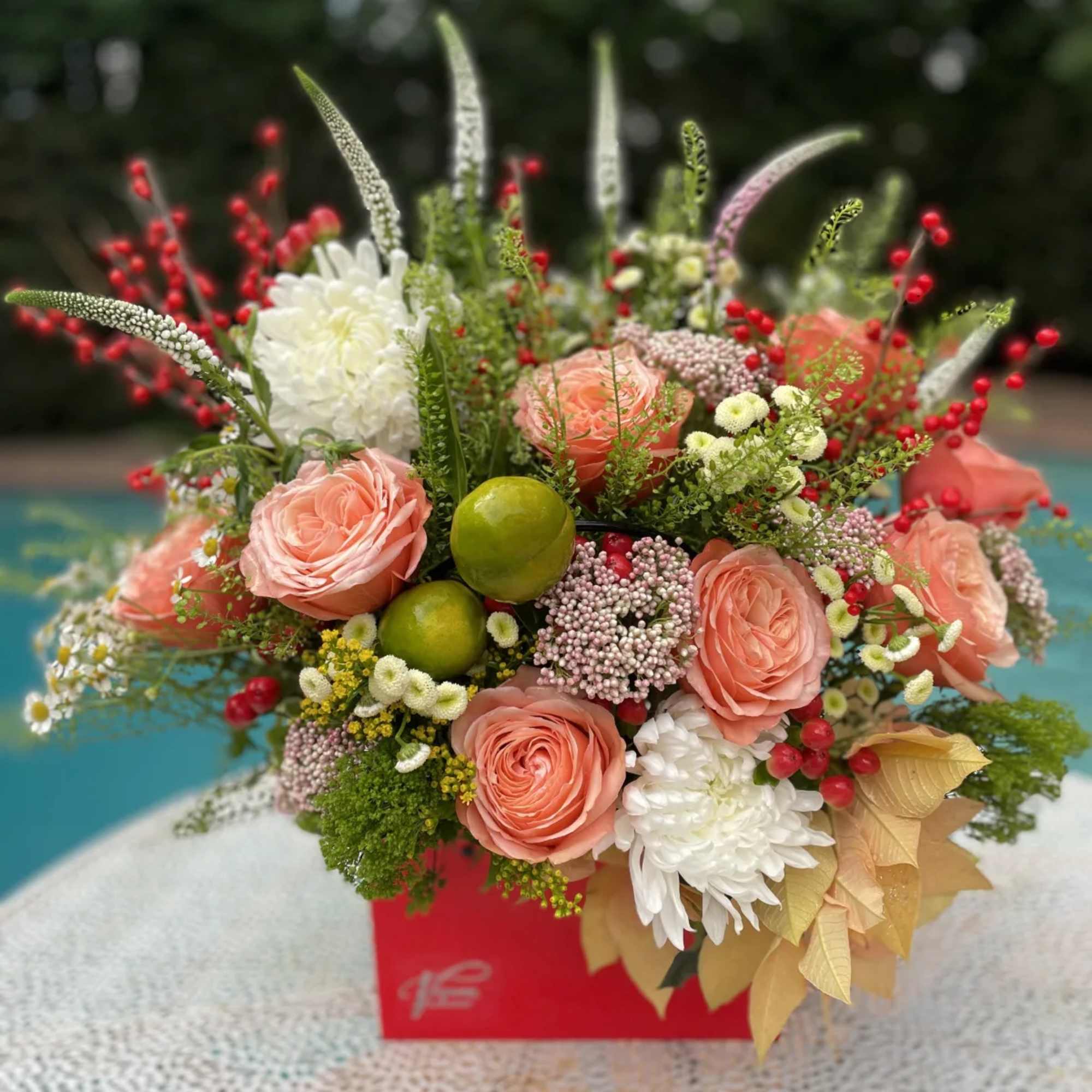 Pink roses and white chrysanthemums in a red box with berries and fruit