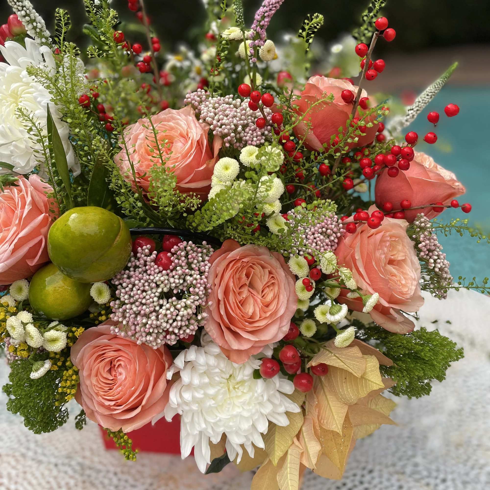Peach roses with white blooms and red berries in a mixed bouquet