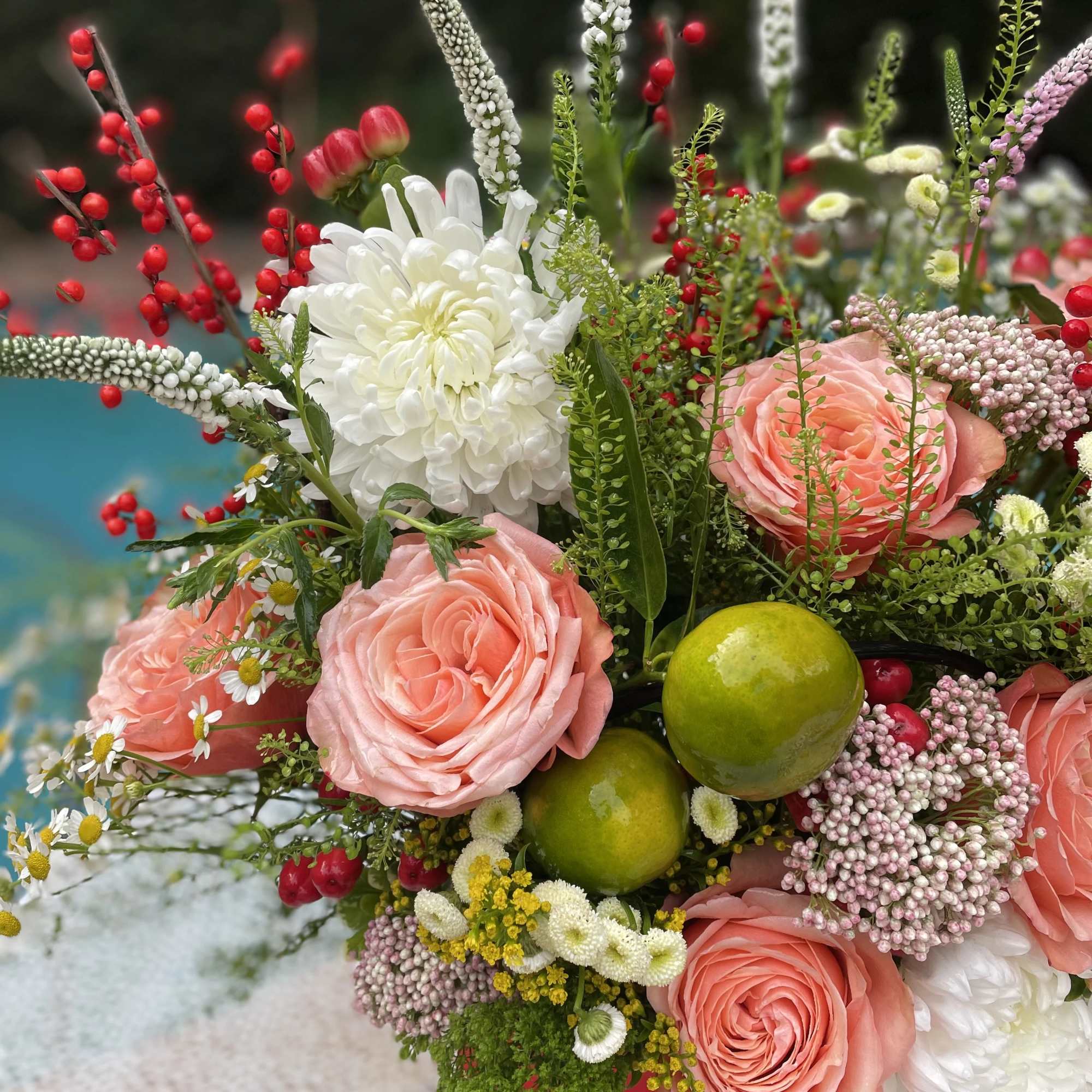Bouquet of pink roses, white chrysanthemums, and red berry stems with green fruit accents