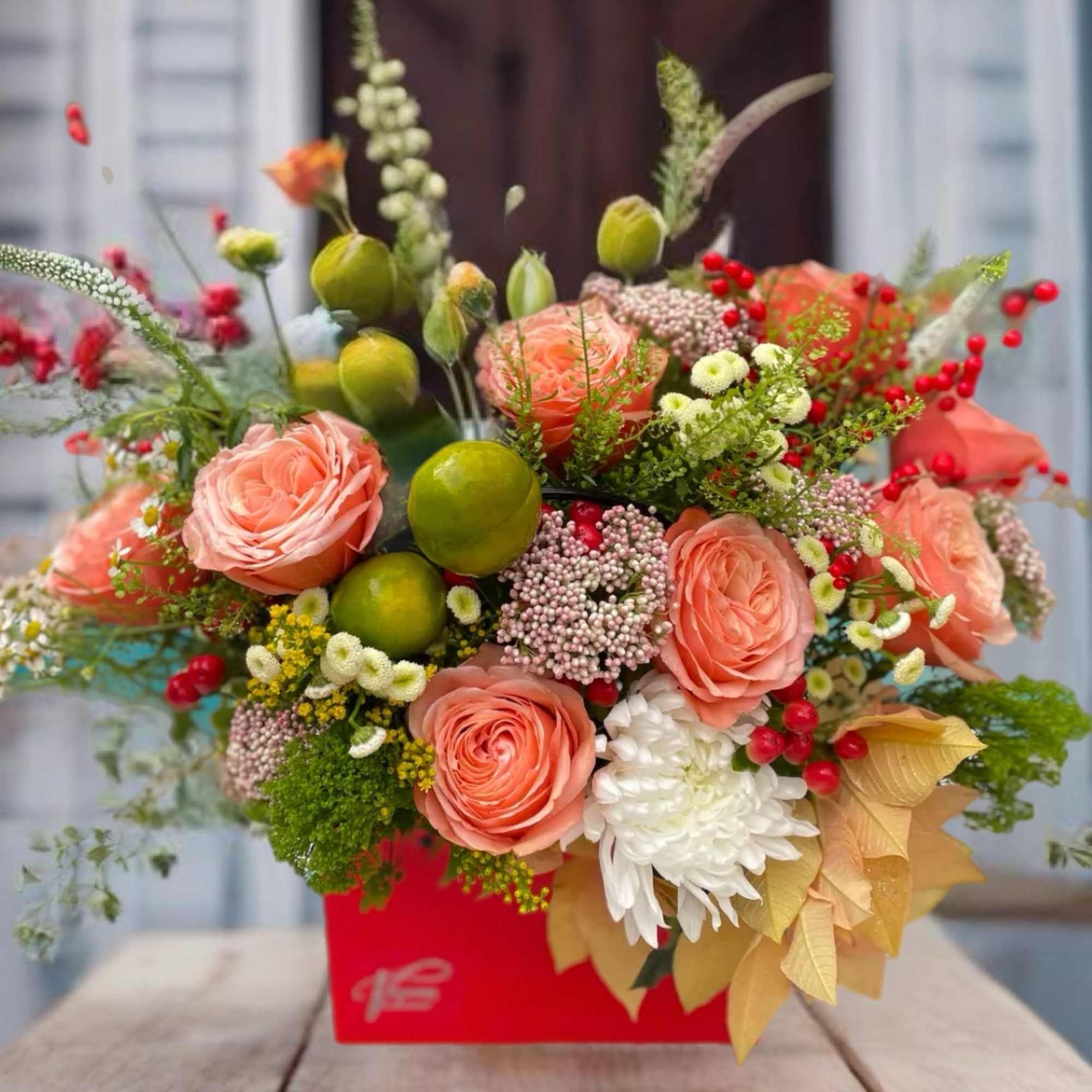 Peach roses and mixed flowers arranged in a red box