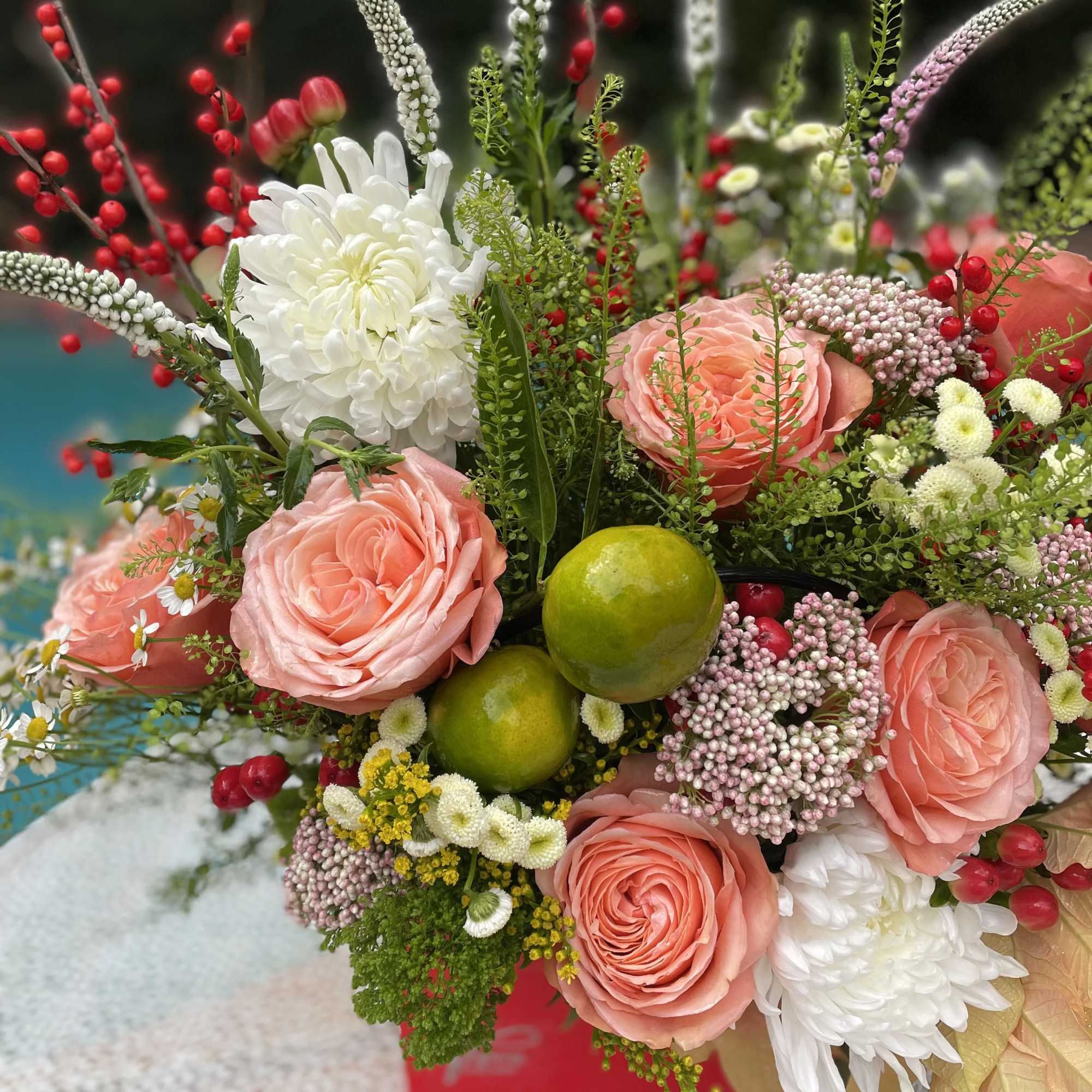 Bouquet of peach roses and white chrysanthemums with berries and green fruit