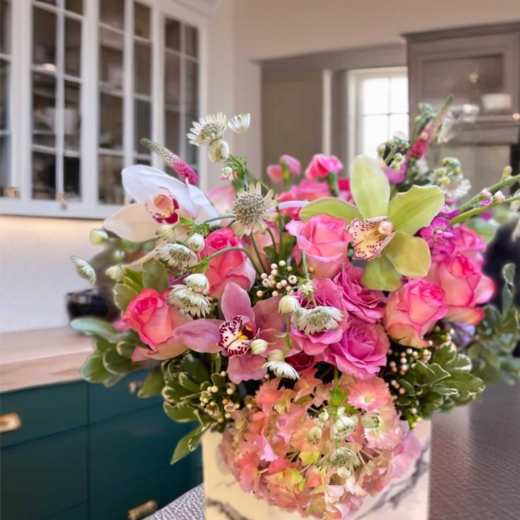 Pink roses and orchids arranged in a square vase
