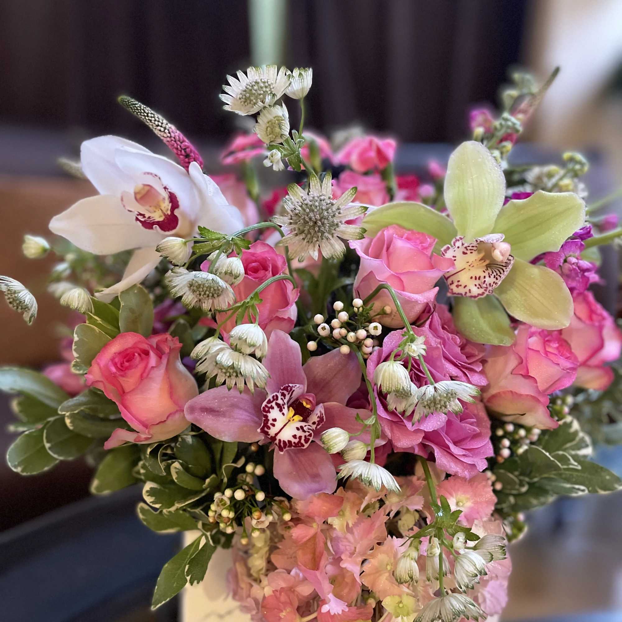 Pink and white floral arrangement with roses and orchids in a box