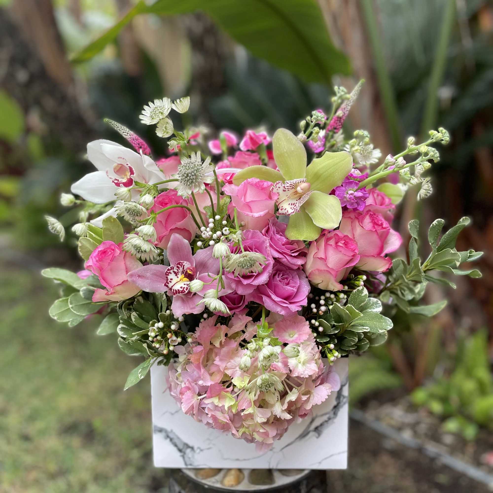 Pink and white floral arrangement in a decorative box