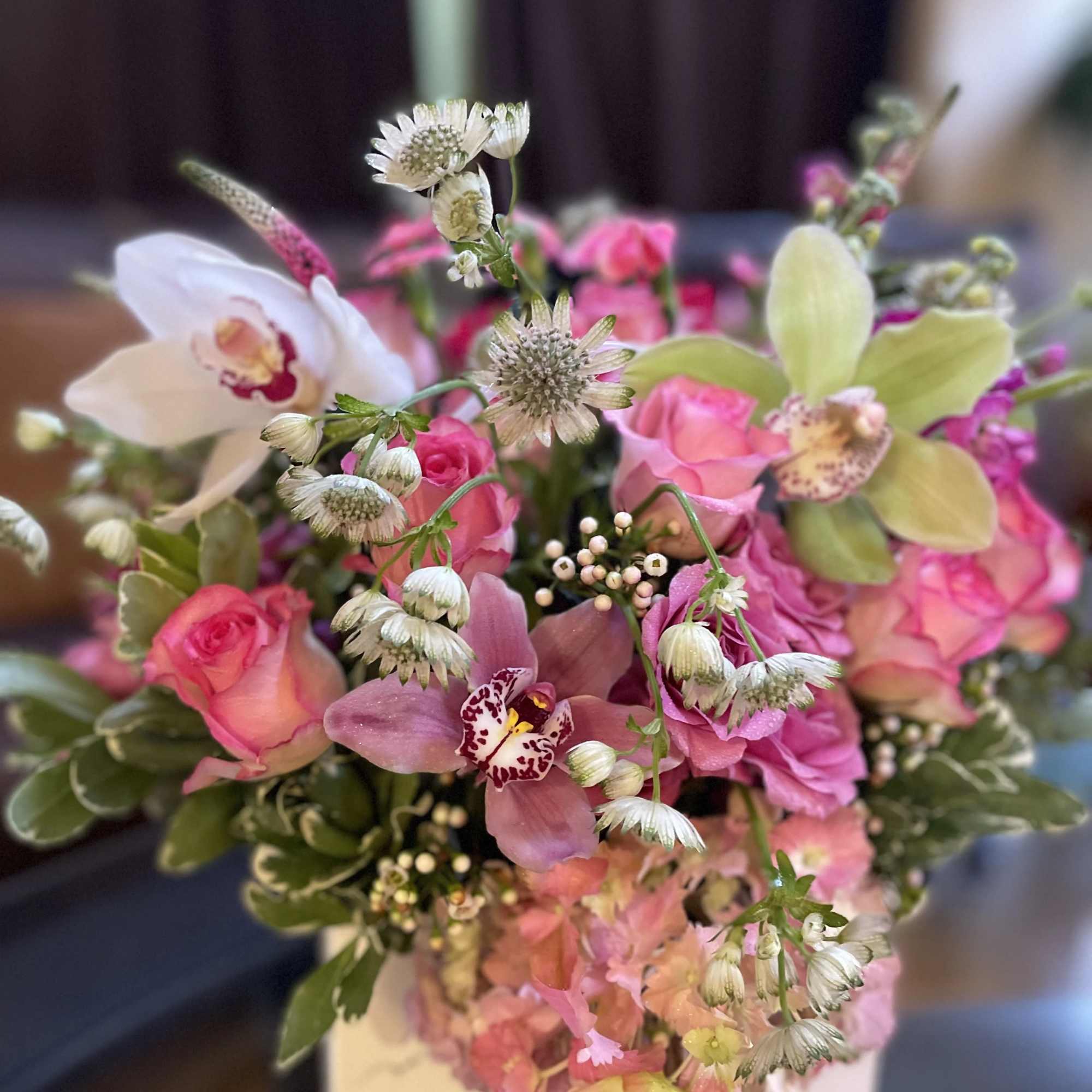 Pink and white floral arrangement in a white box with orchids and roses