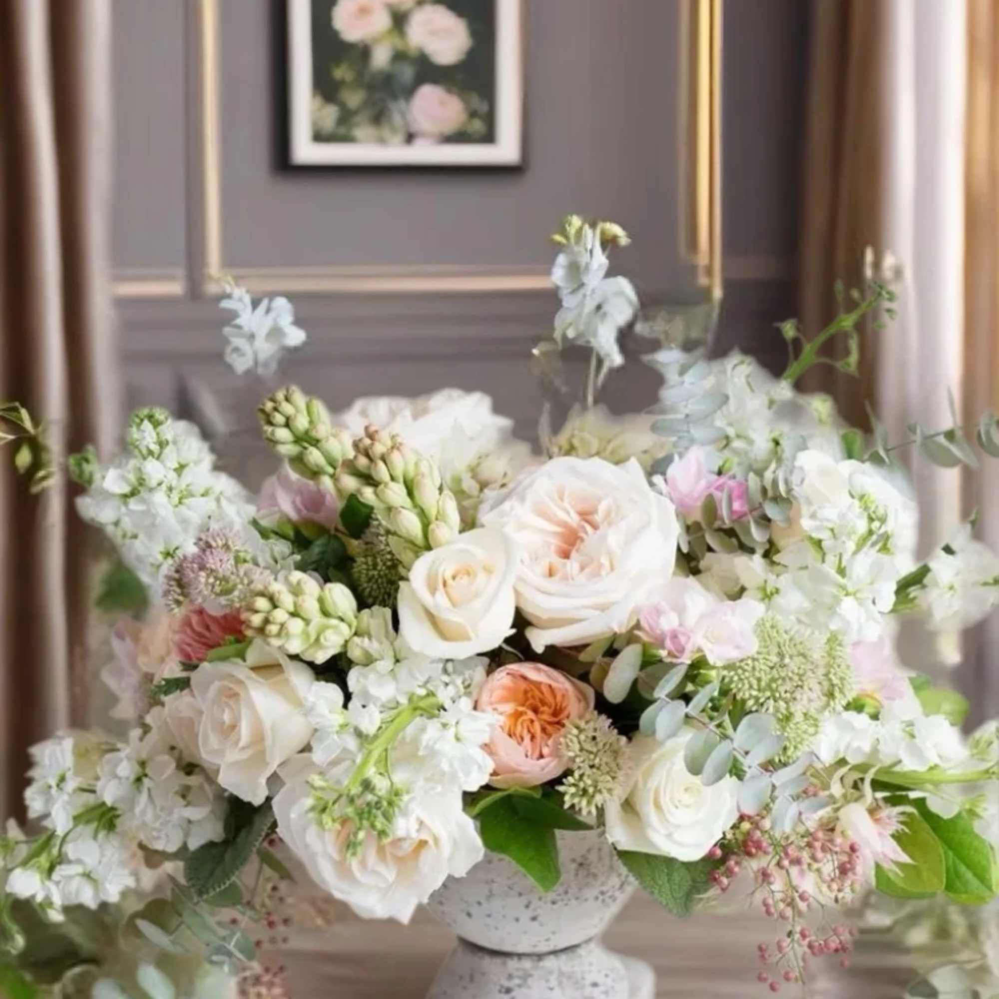 Pastel floral arrangement in a stone pedestal vase