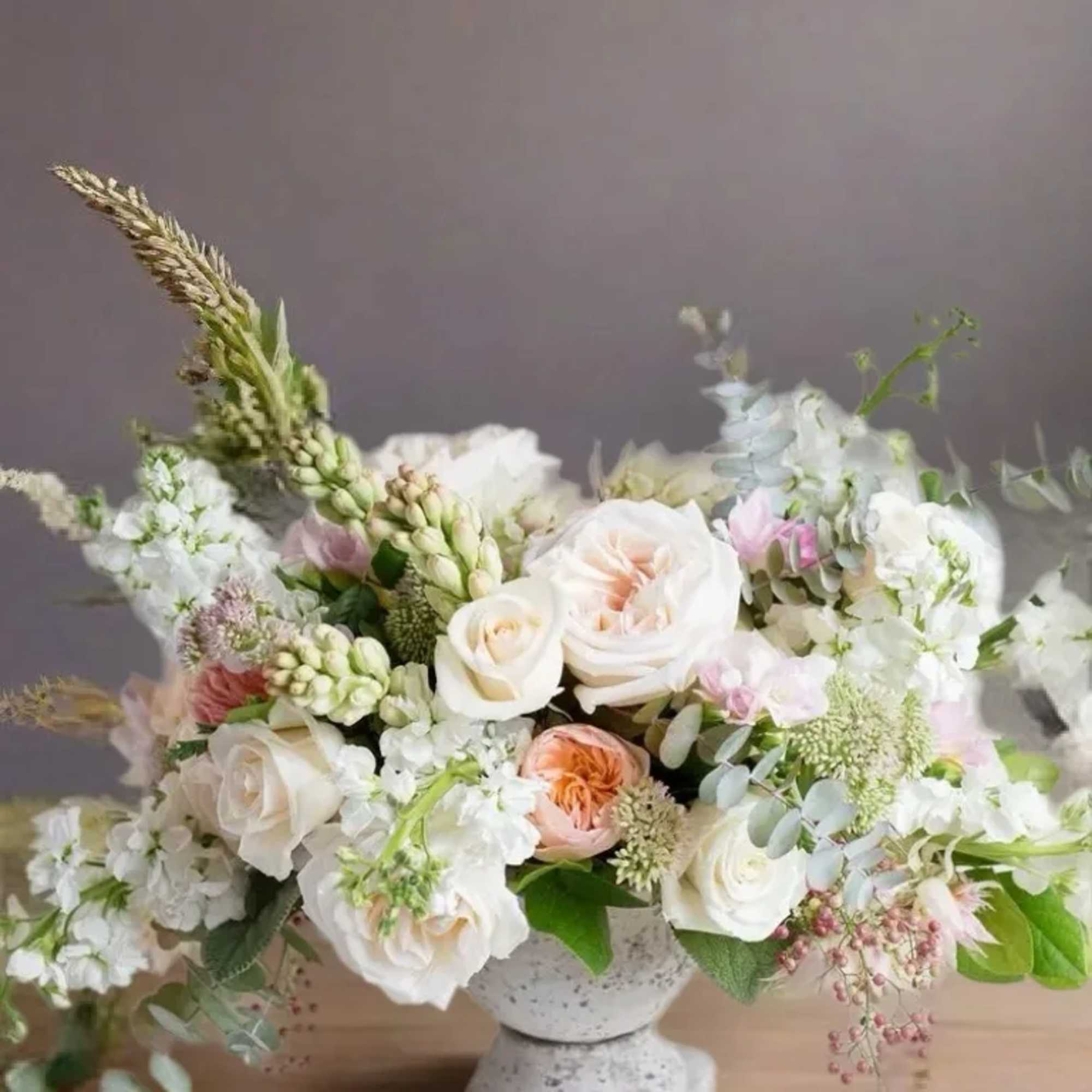 White and blush floral arrangement in a stone pedestal vase
