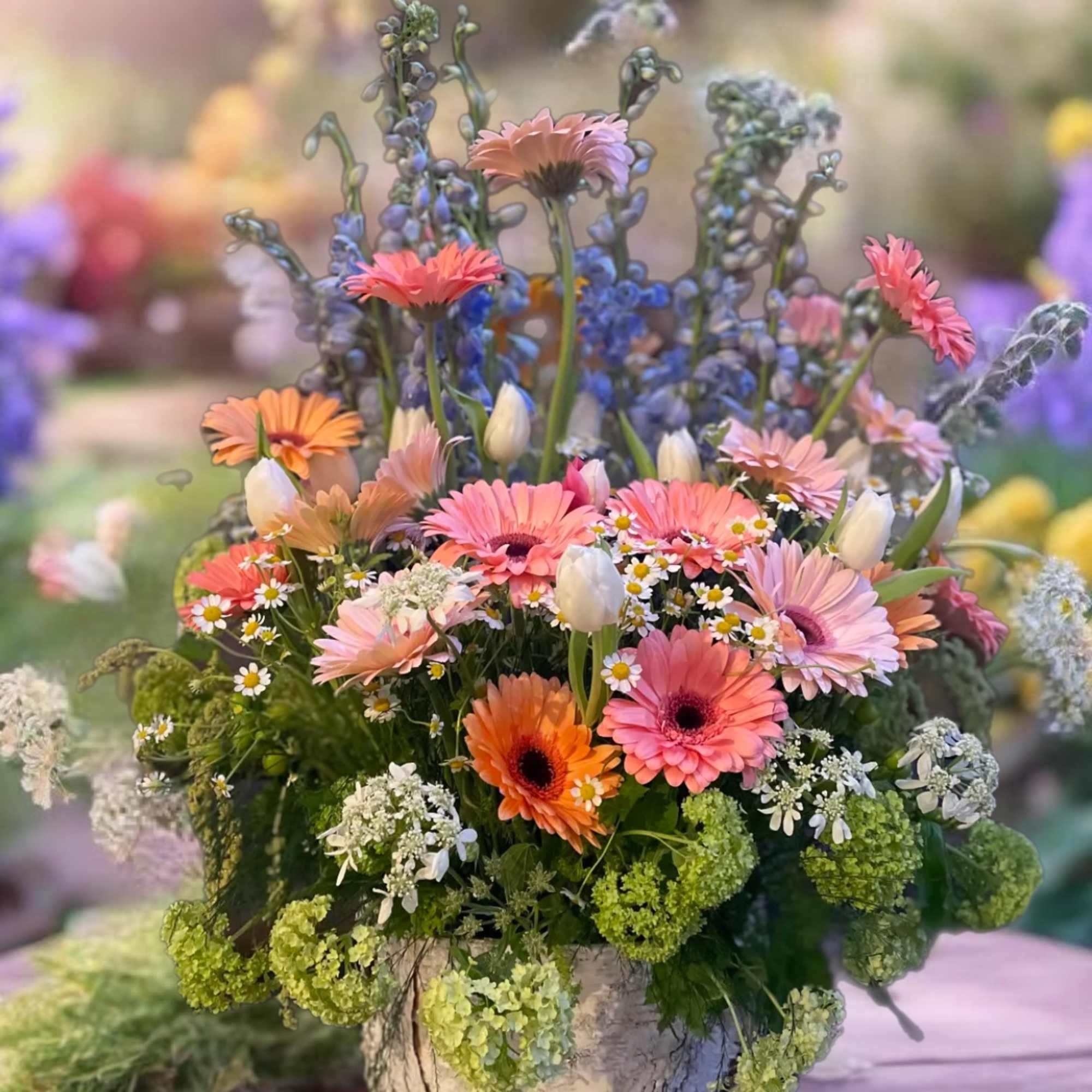 Mixed pink and orange flowers in a rustic vase