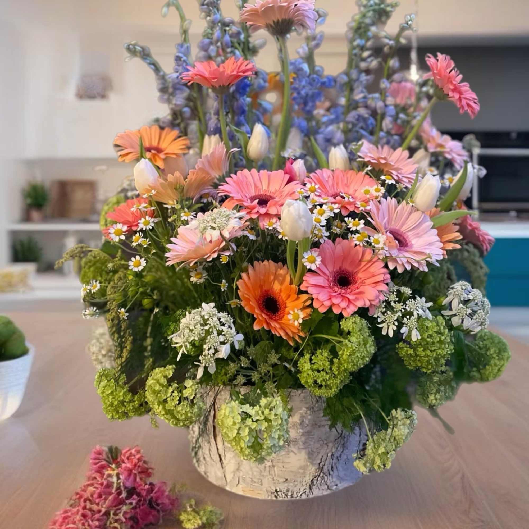 Mixed bouquet in a white container with pink and orange daisies