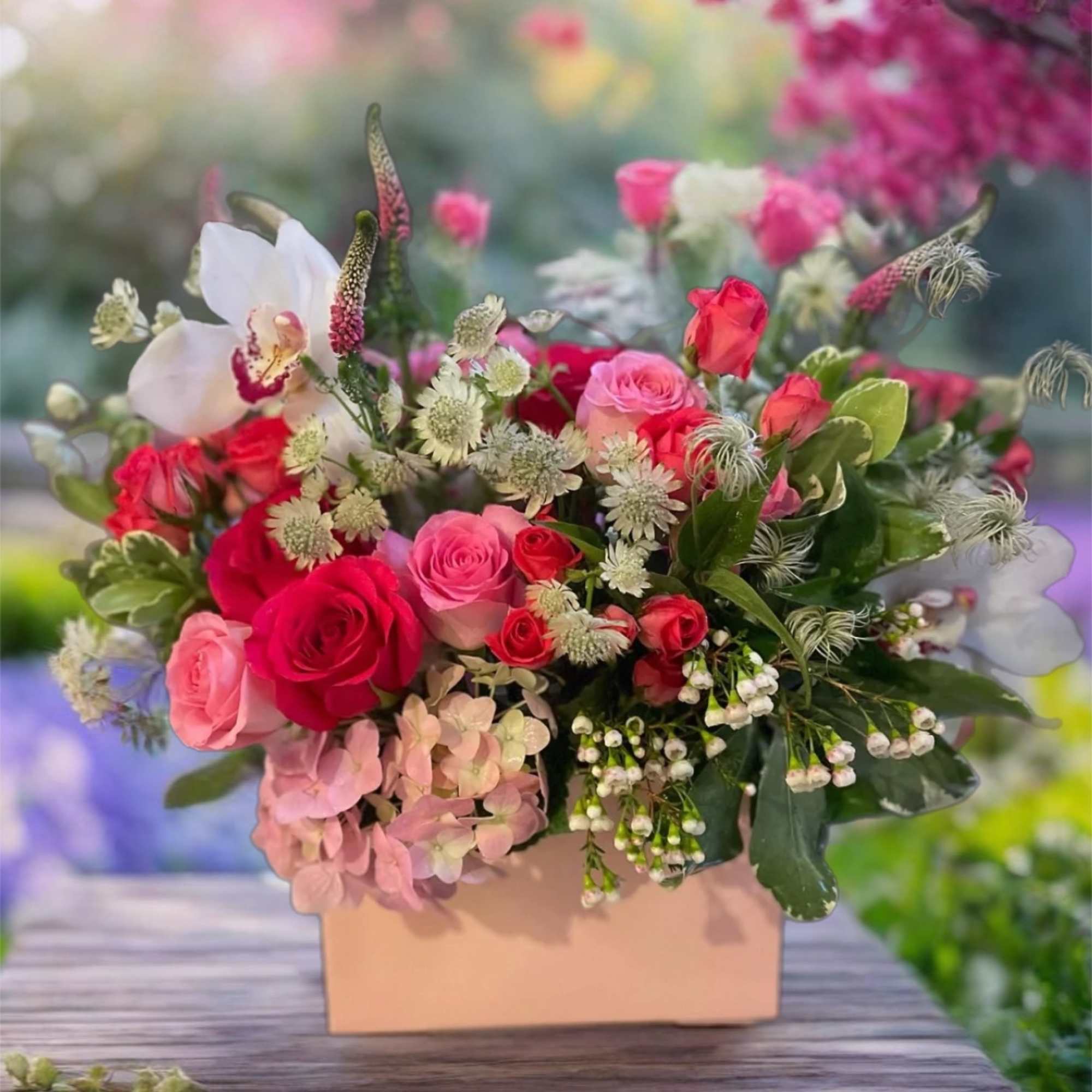 Pink and red roses arranged in a peach box with white accent flowers