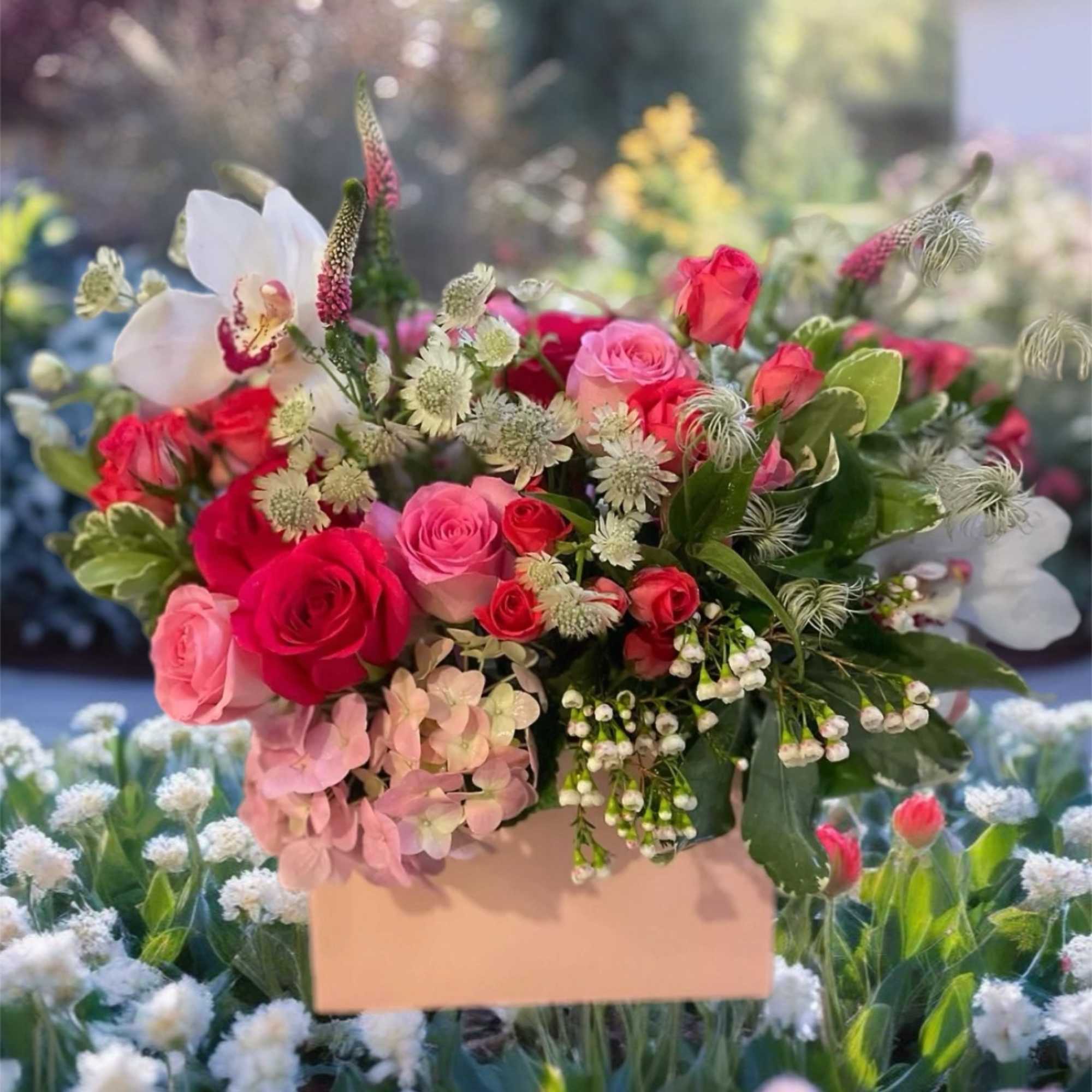 Pink and red rose bouquet with white orchids in a pale box