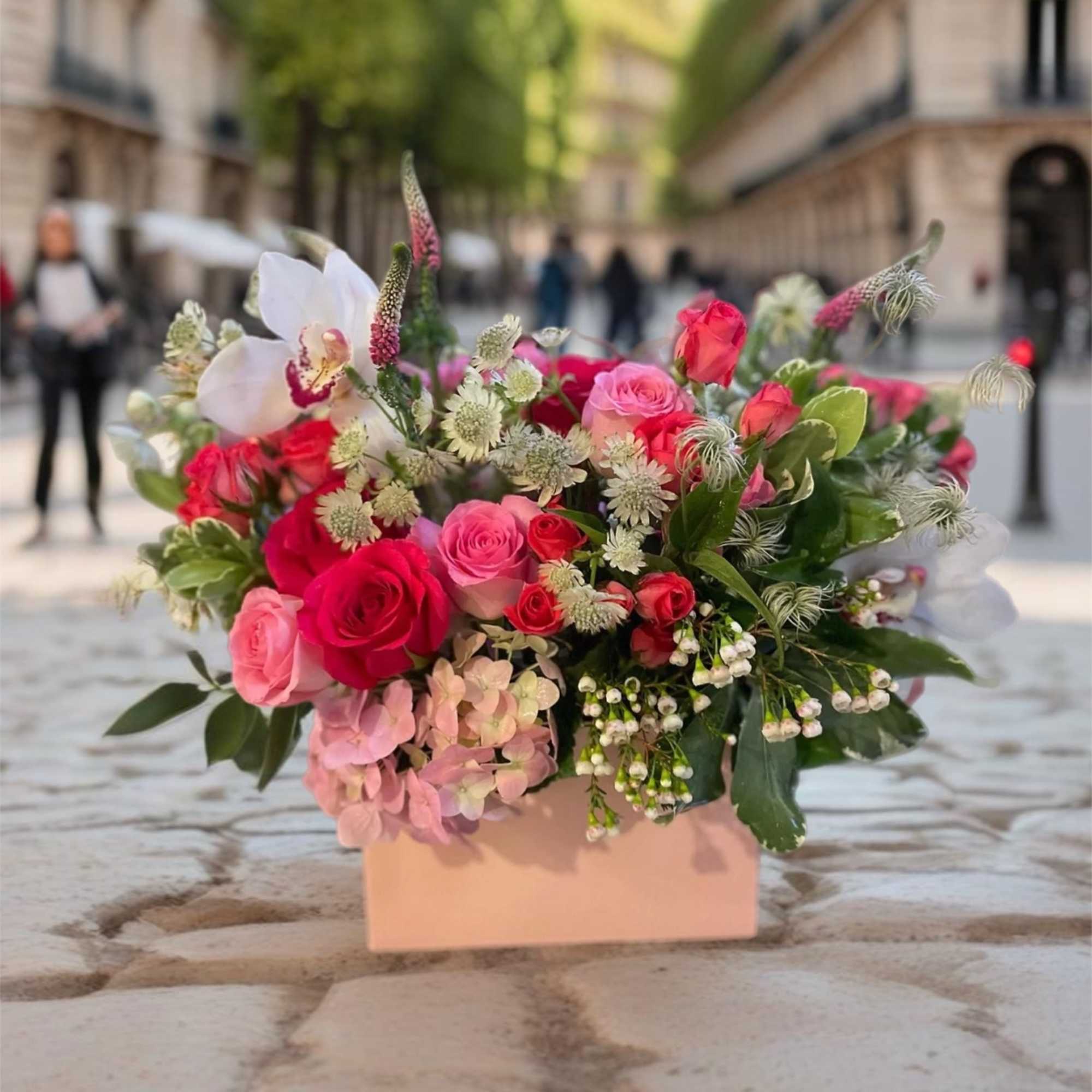 Pink and red rose arrangement in a blush box with white orchids