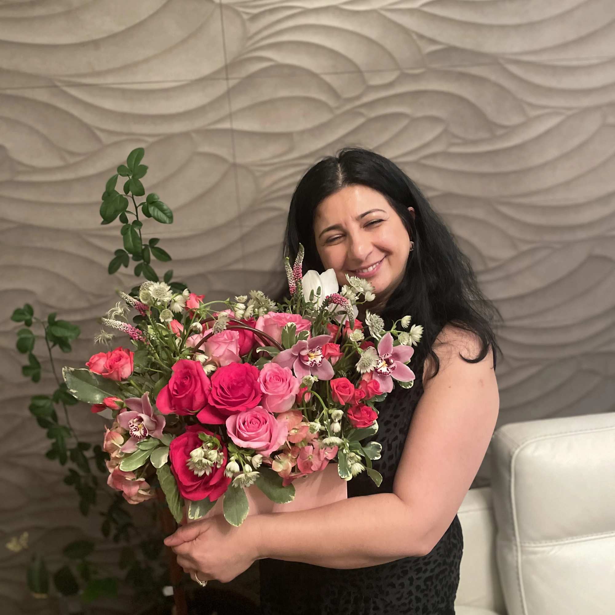 Woman holding a bouquet of pink and hot pink roses with orchids