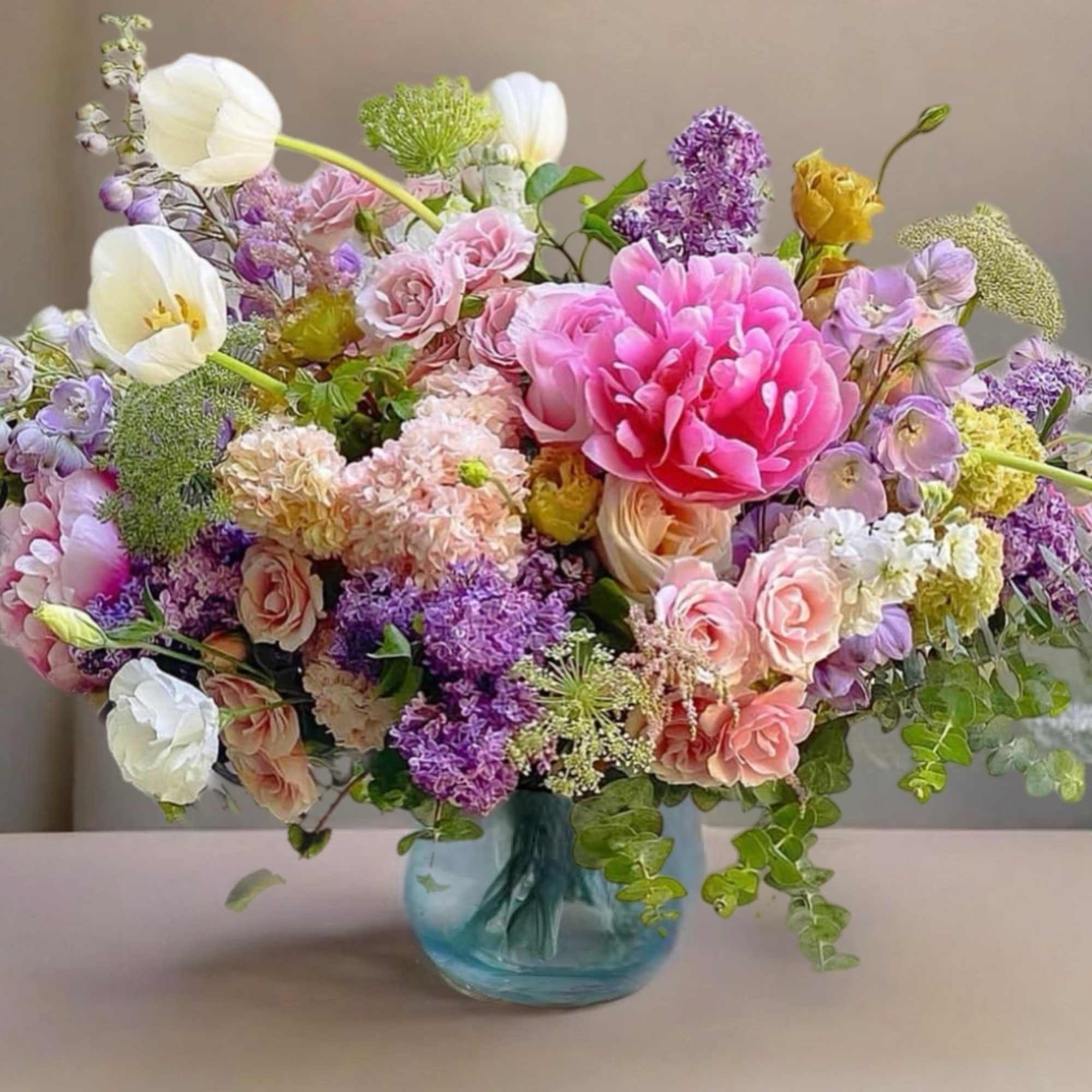 Mixed pink, purple, and white flowers in a blue glass vase