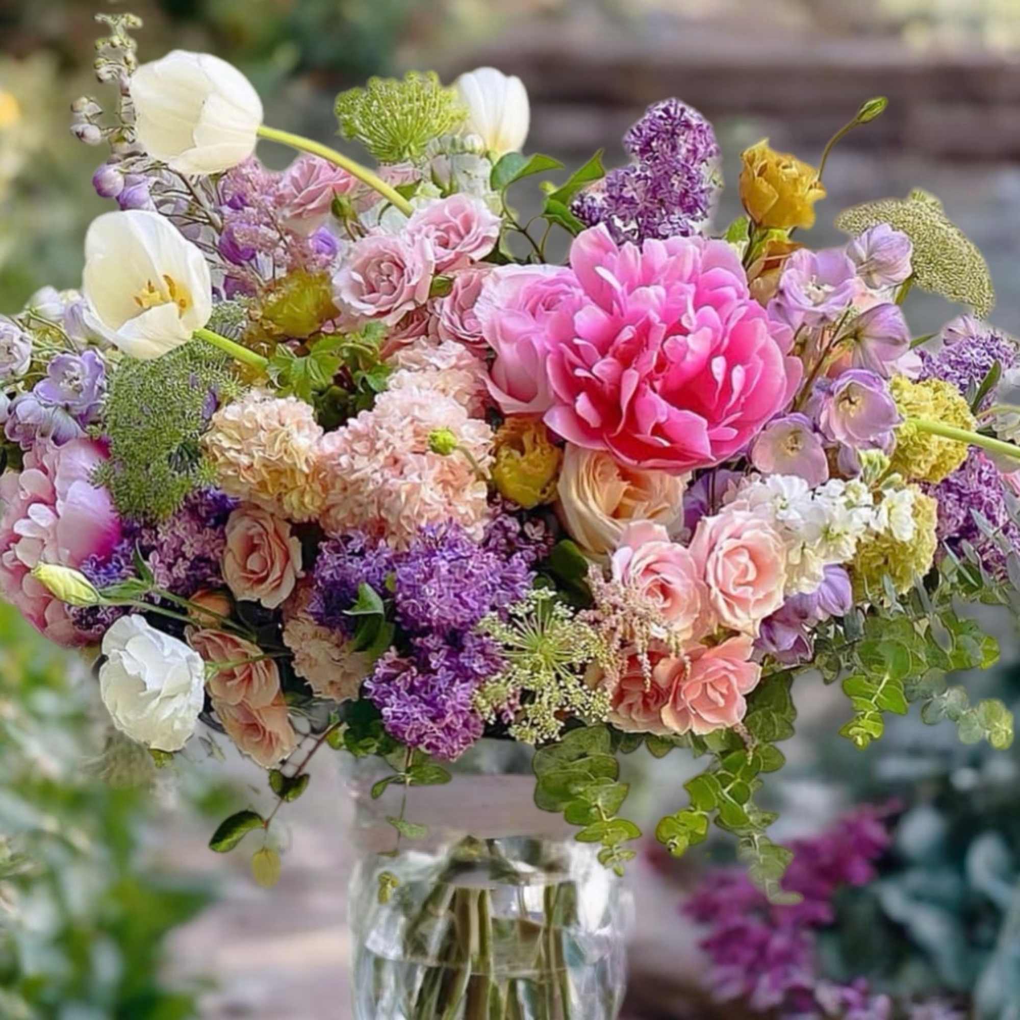 Mixed bouquet of pink, purple, and white flowers in a glass vase