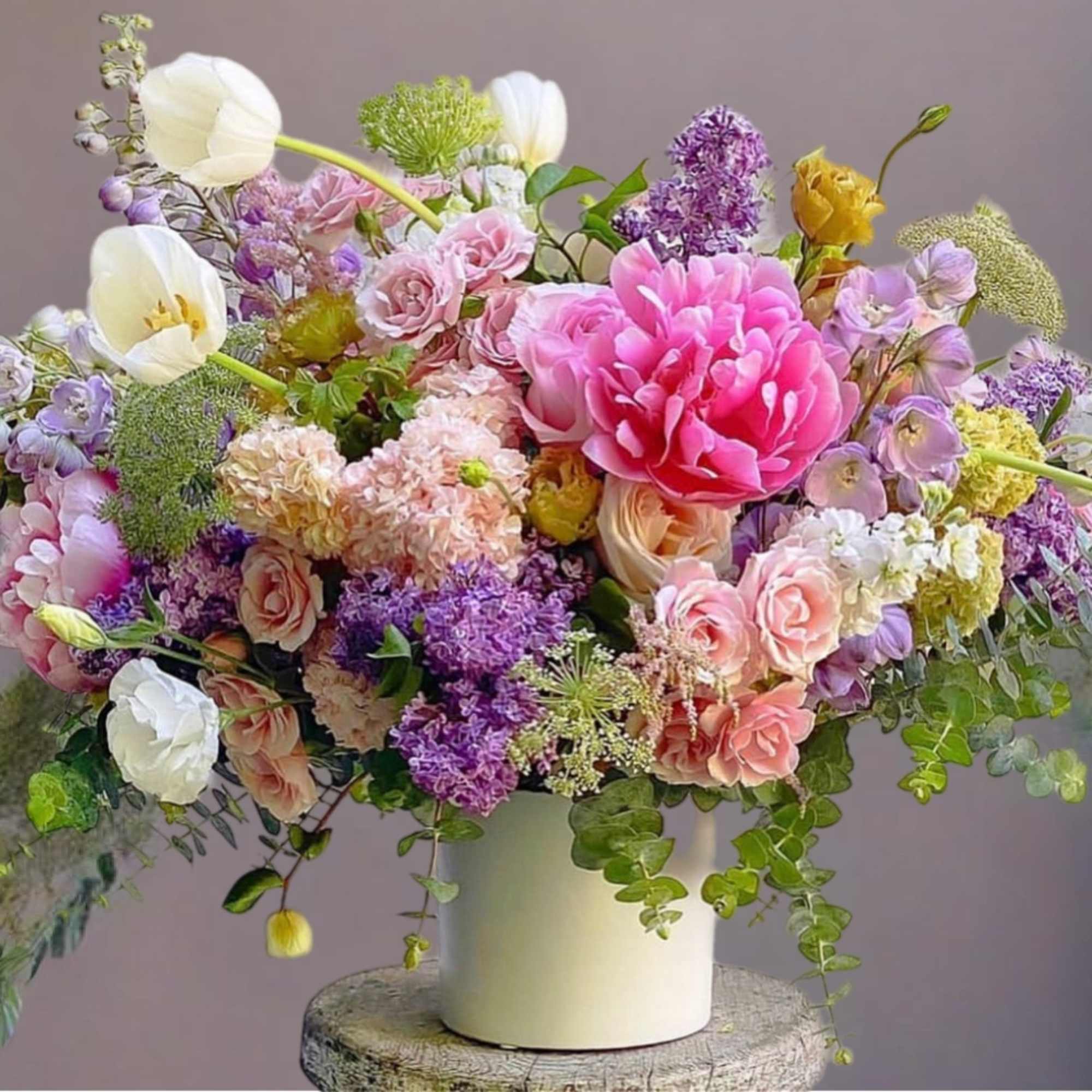 Large pastel bouquet in a white vase with pink, purple, and white blooms