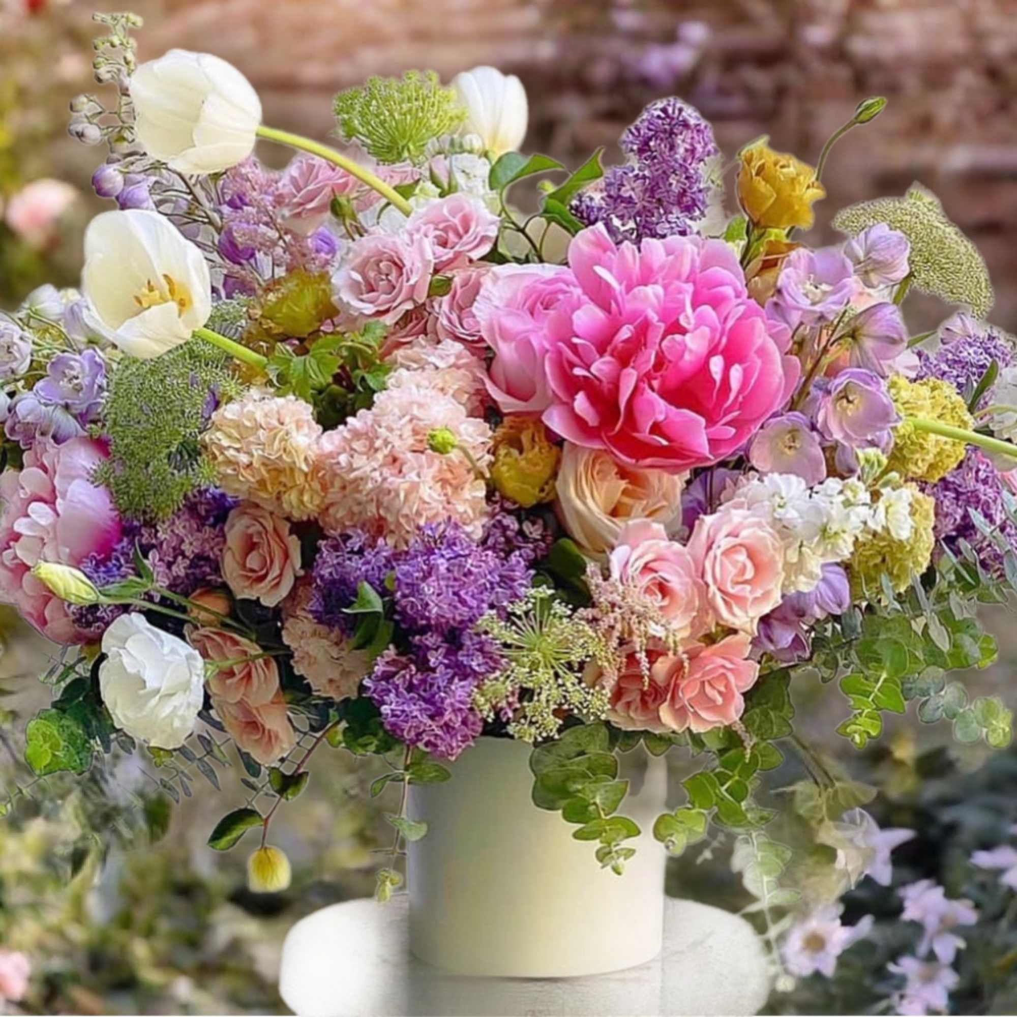 Mixed pastel bouquet in a white vase with pink, purple, and white blooms
