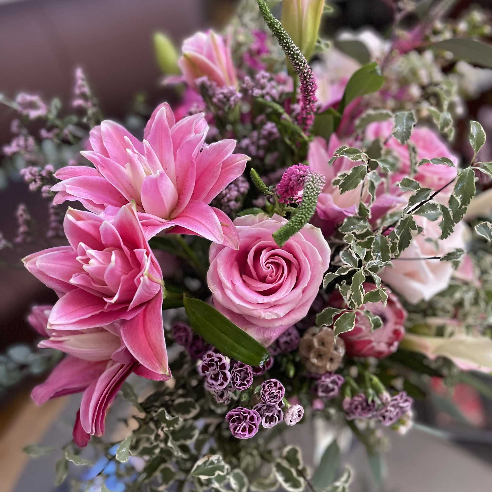 Pink lilies and roses in a mixed bouquet with variegated foliage