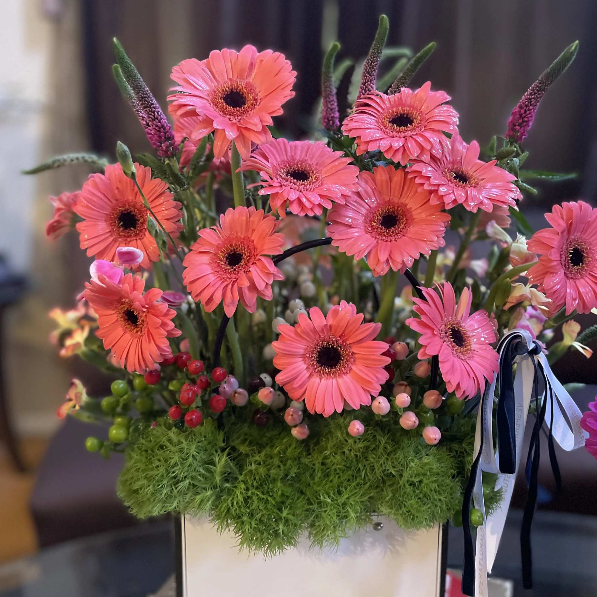 Pink gerbera daisies arranged in a white box with green moss