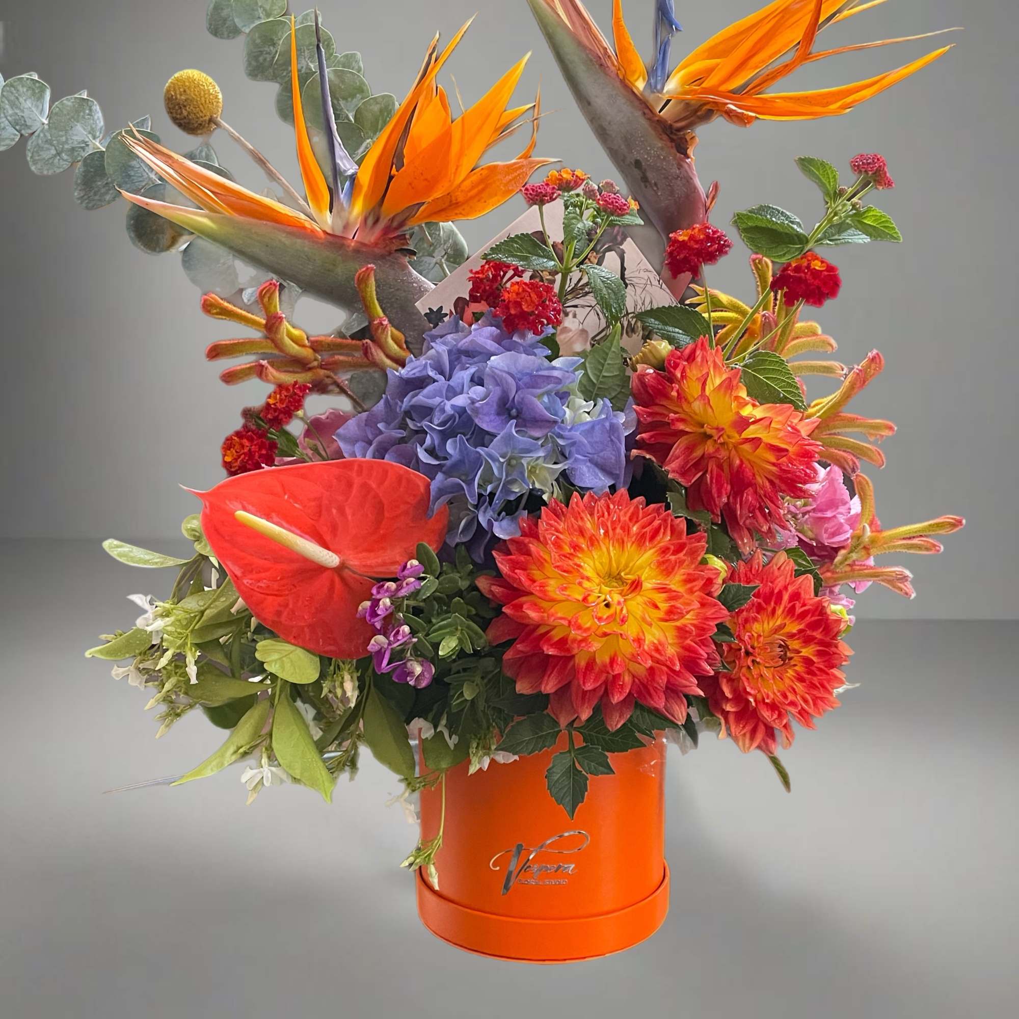 Tropical bouquet with bird-of-paradise, dahlias, and anthurium in an orange box