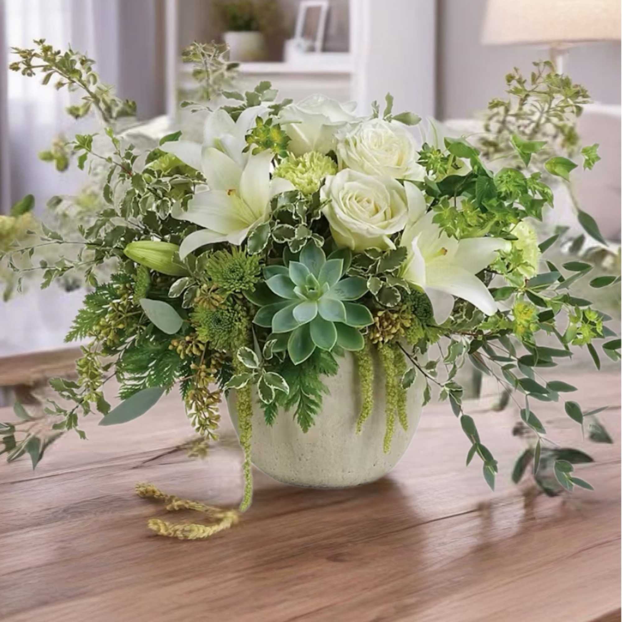 White roses and lilies in a ceramic vase with trailing greenery