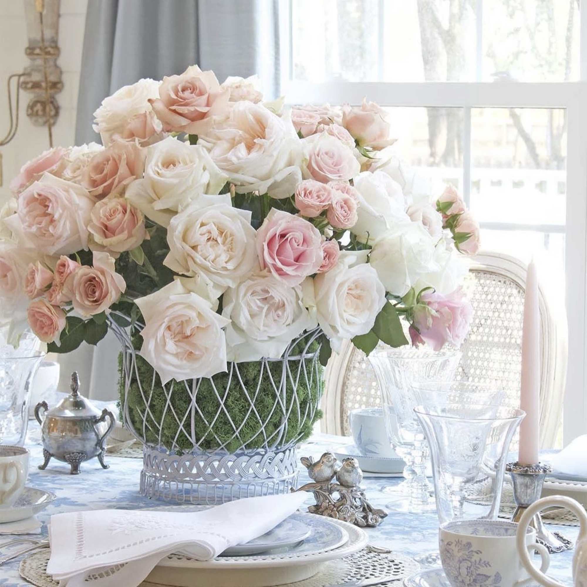 Blush and white roses arranged in a decorative basket centerpiece