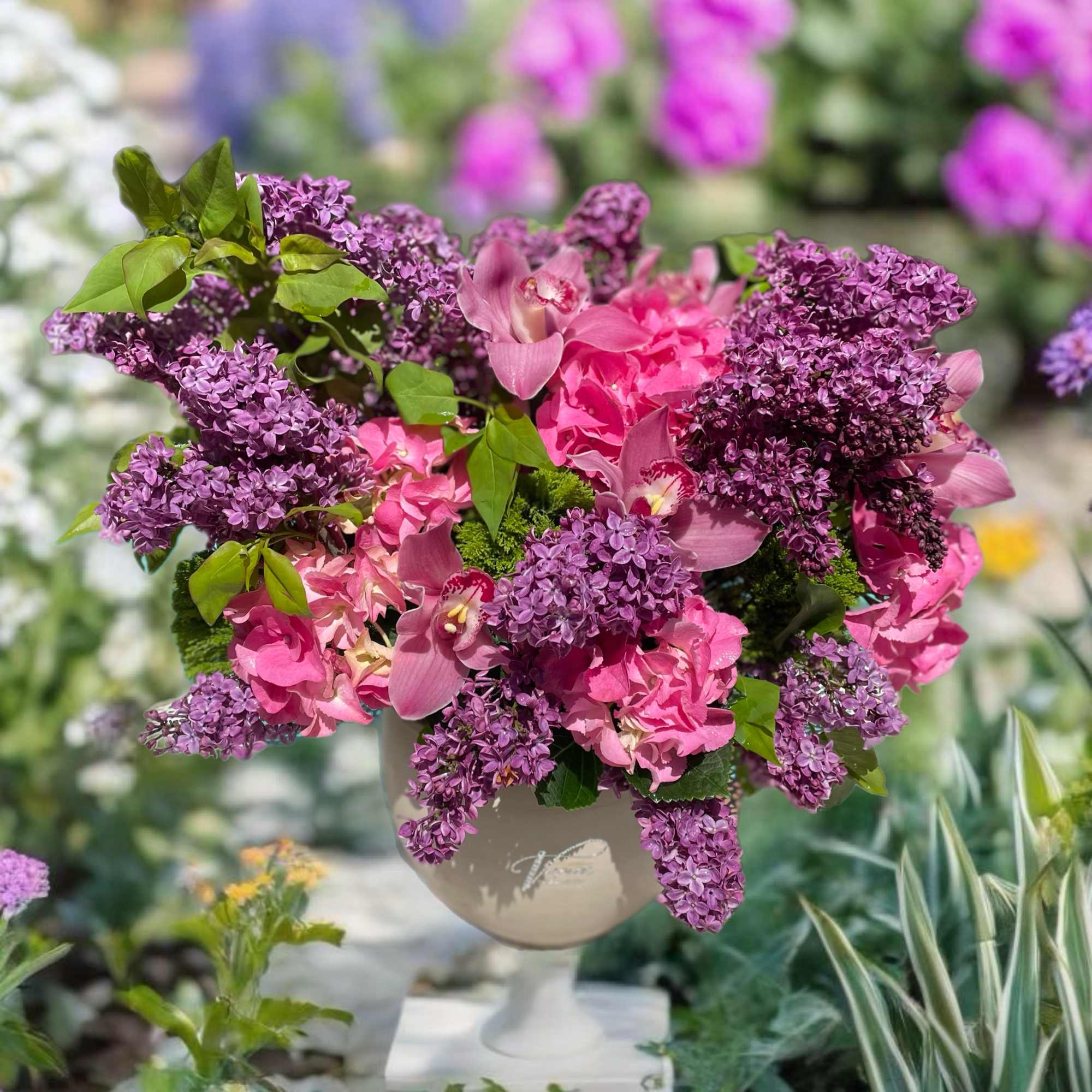 Pink and purple floral arrangement in a pedestal vase