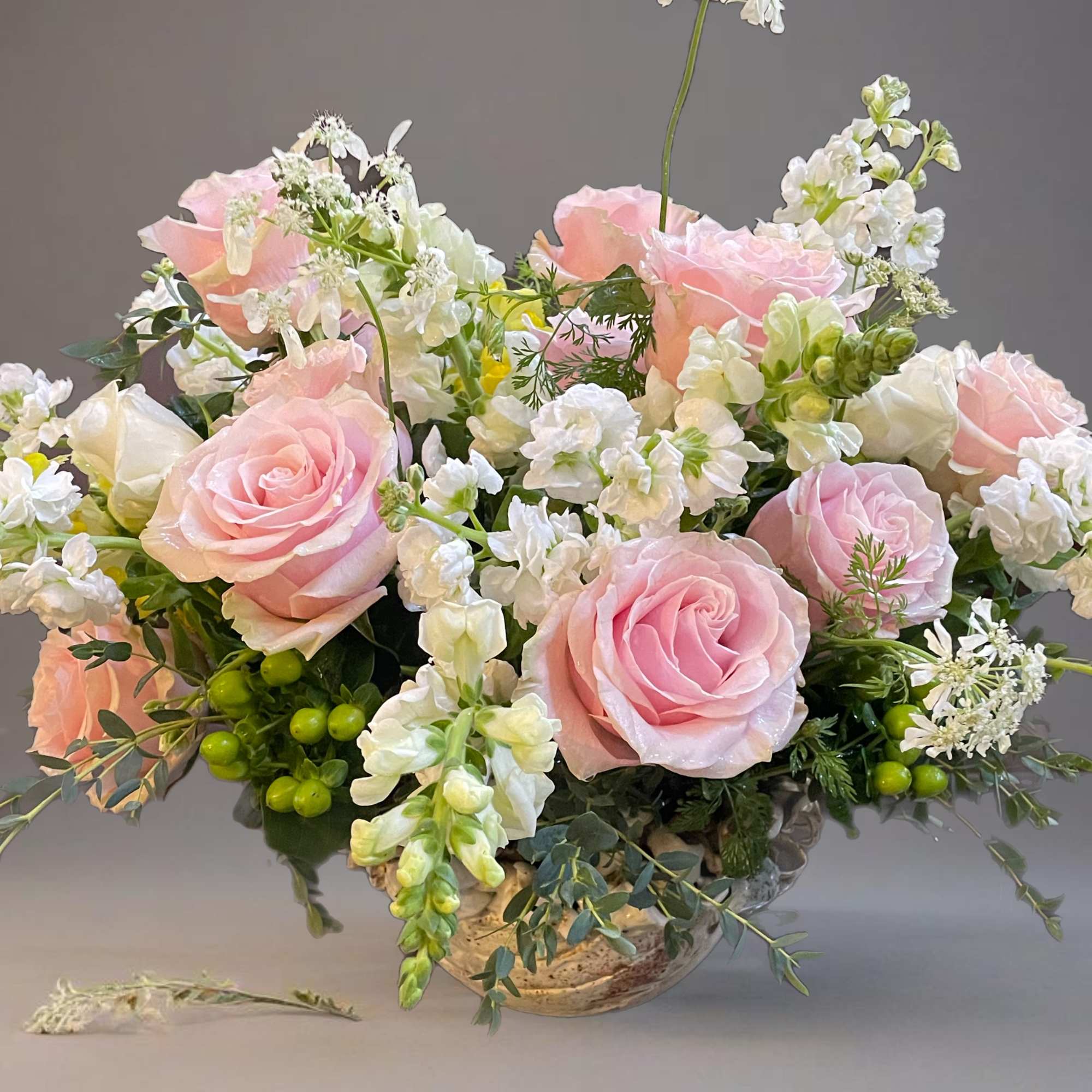 Pink roses and white flowers arranged in a low vase