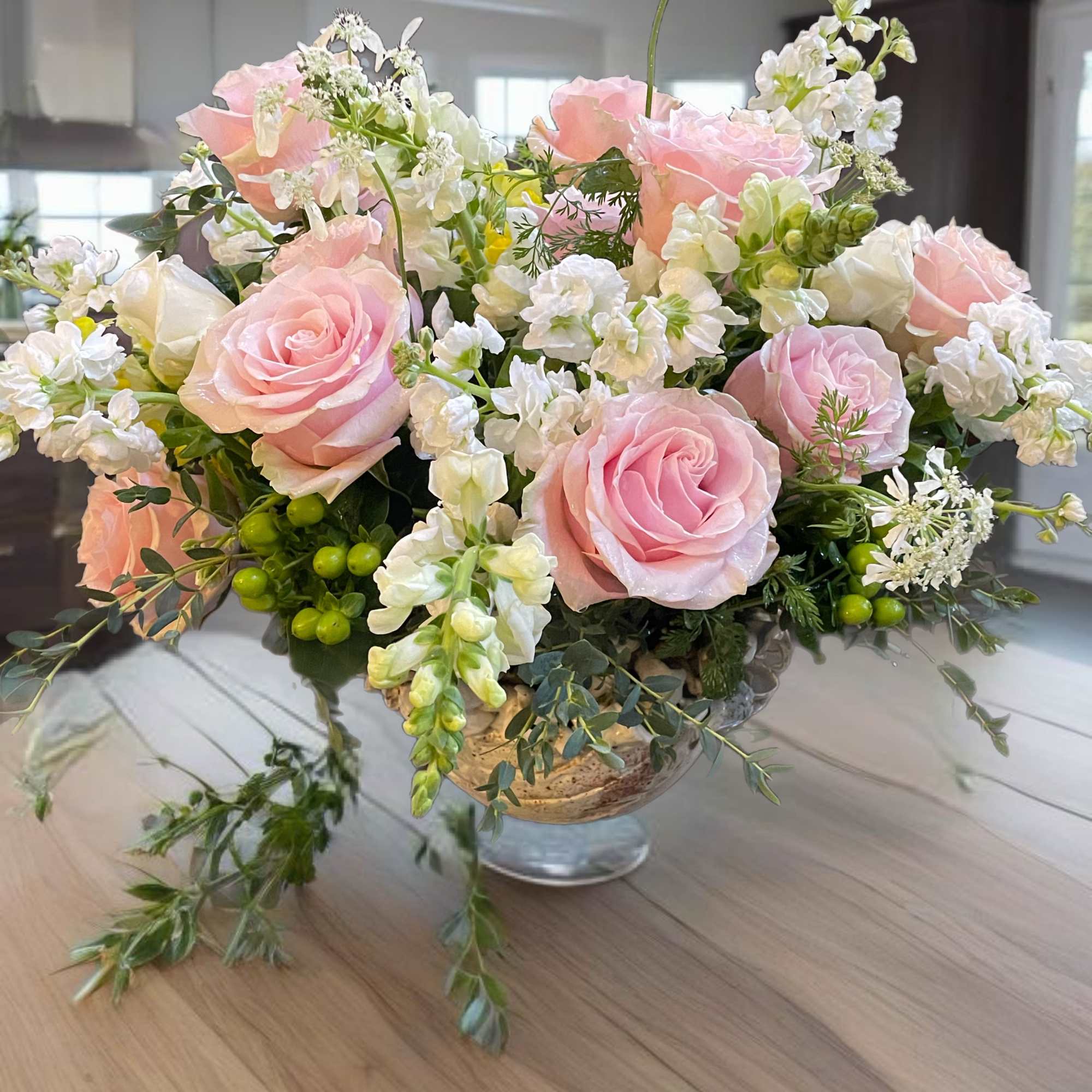 Pink roses and white flowers arranged in a glass vase