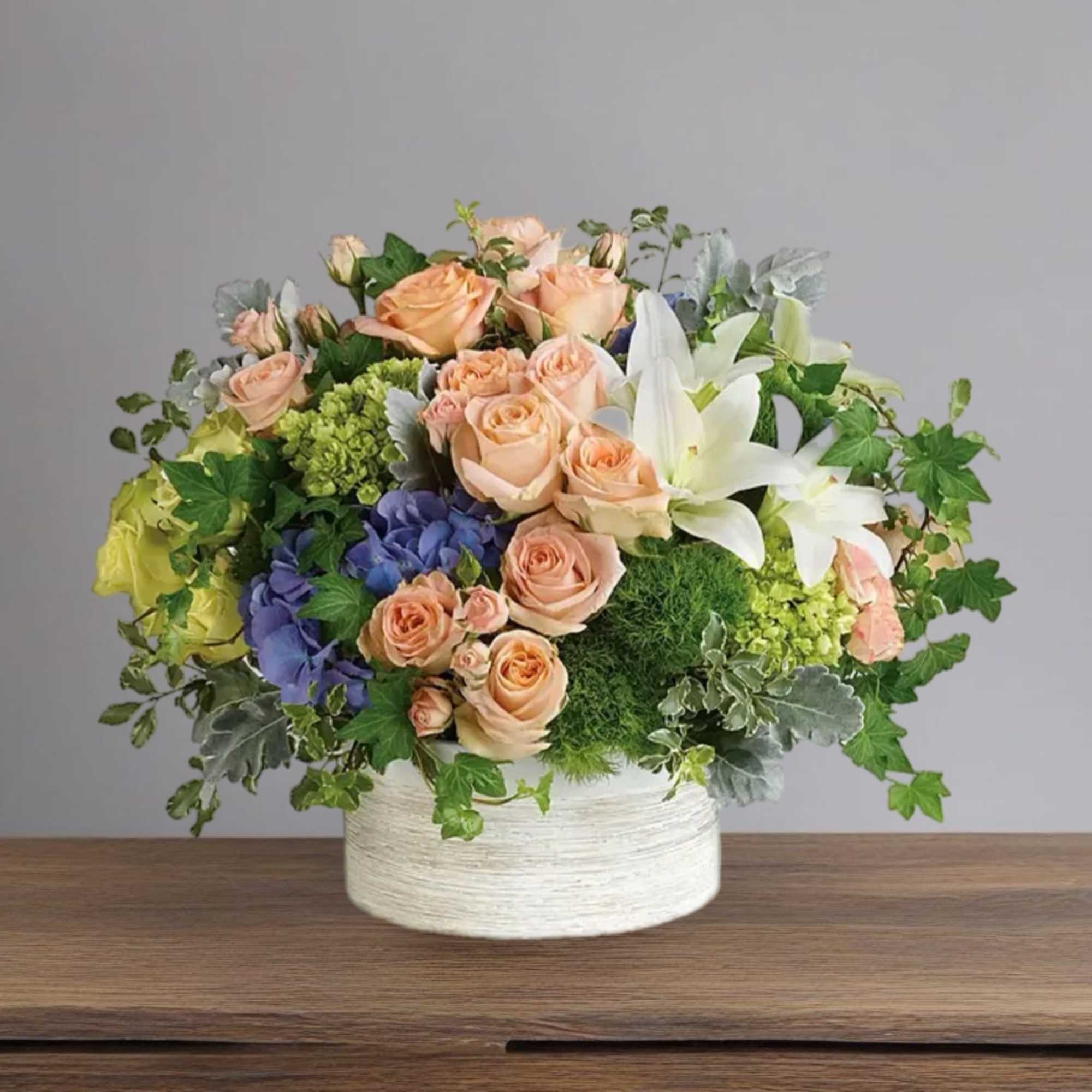 Peach roses and white lilies in a white round vase