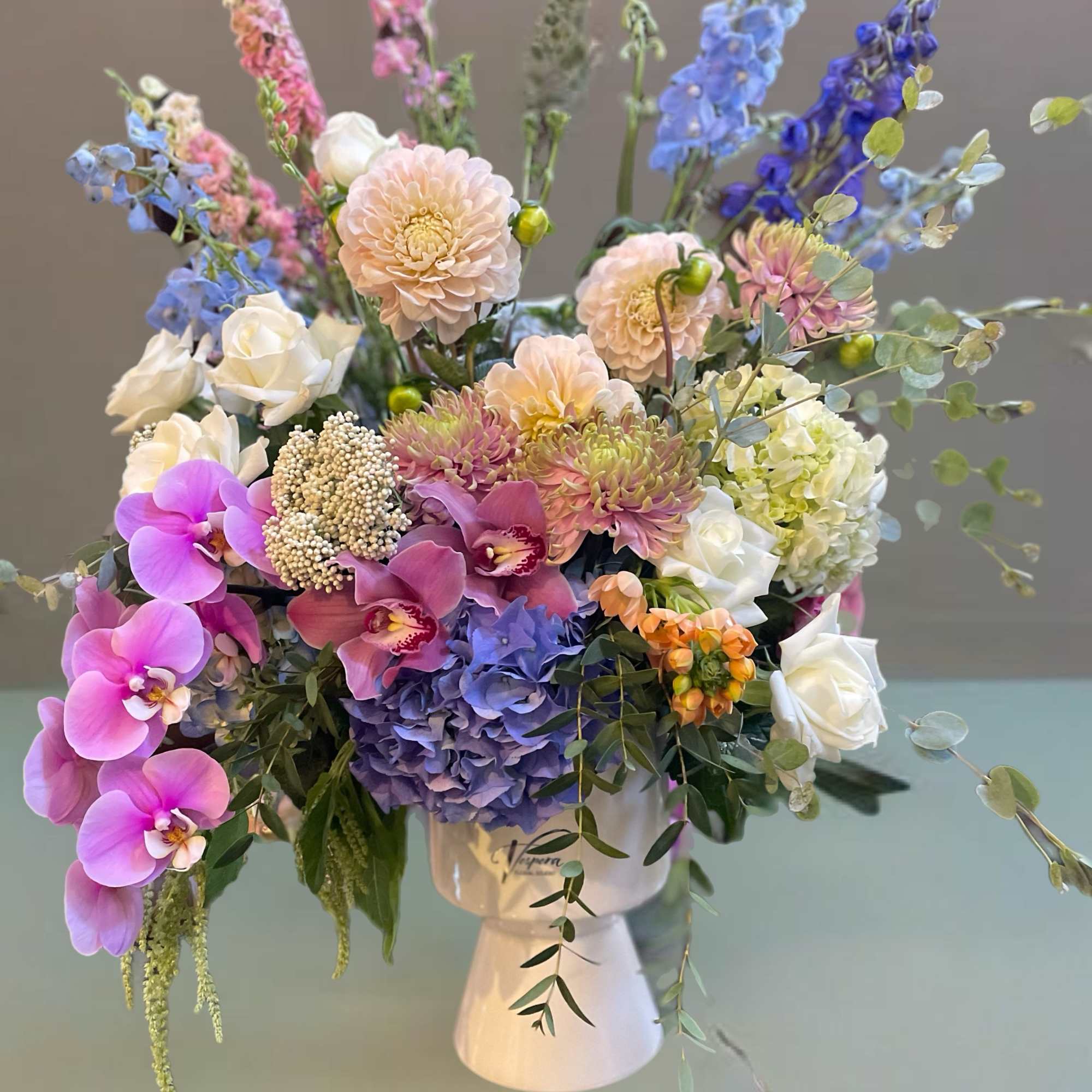 Mixed bouquet in a white vase with pink, blue, purple, and white flowers