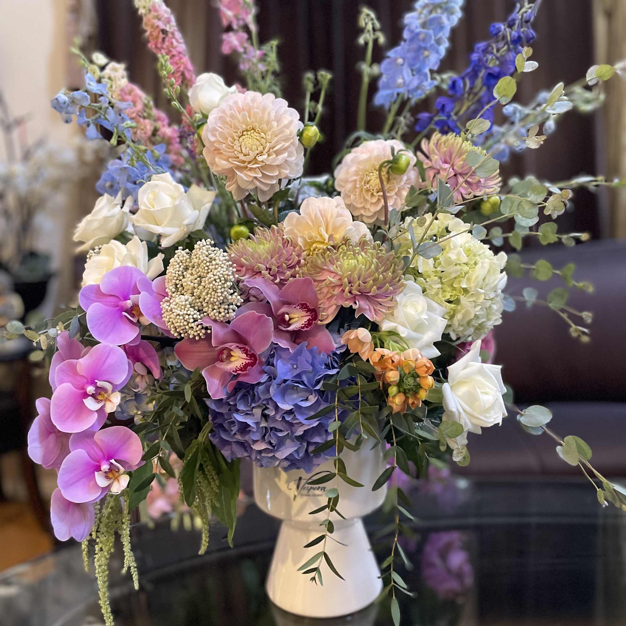 Mixed bouquet of pastel flowers in a white pedestal vase