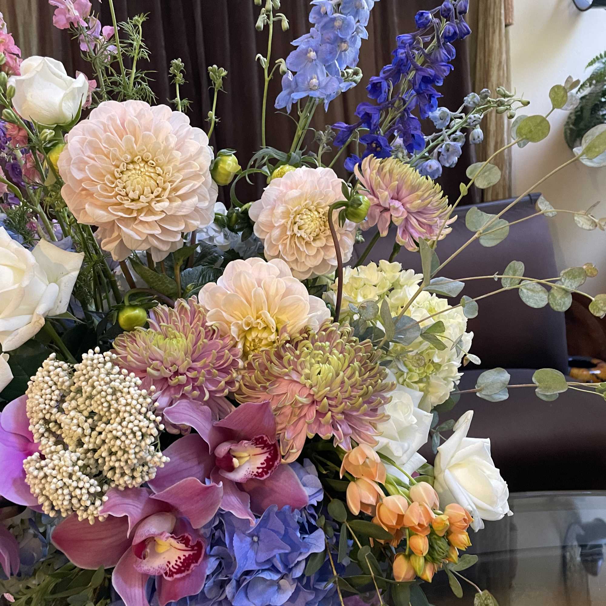 Mixed bouquet with pastel dahlias, orchids, roses, and blue delphinium