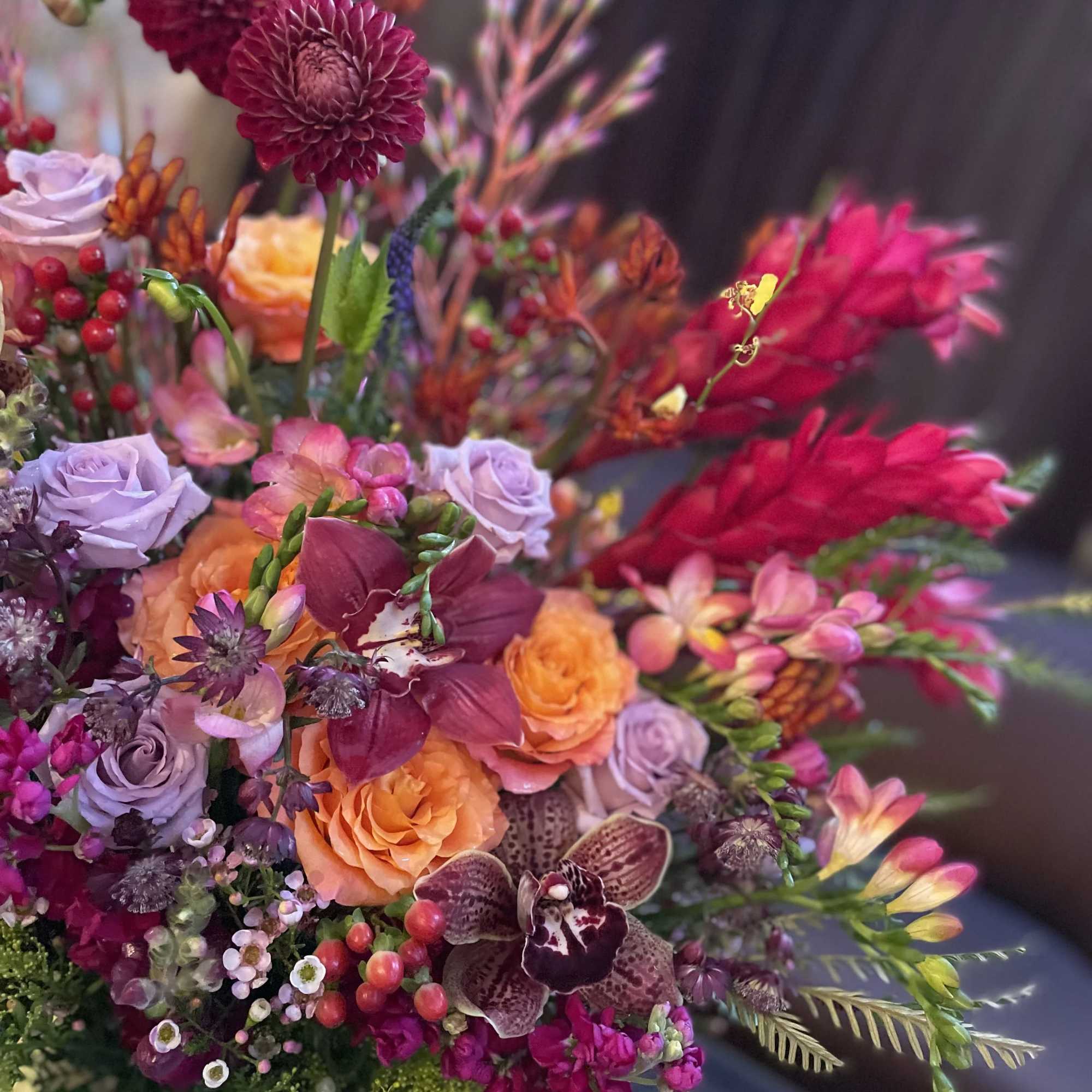 Colorful bouquet with roses, orchids, and dahlias in pink, orange, and purple